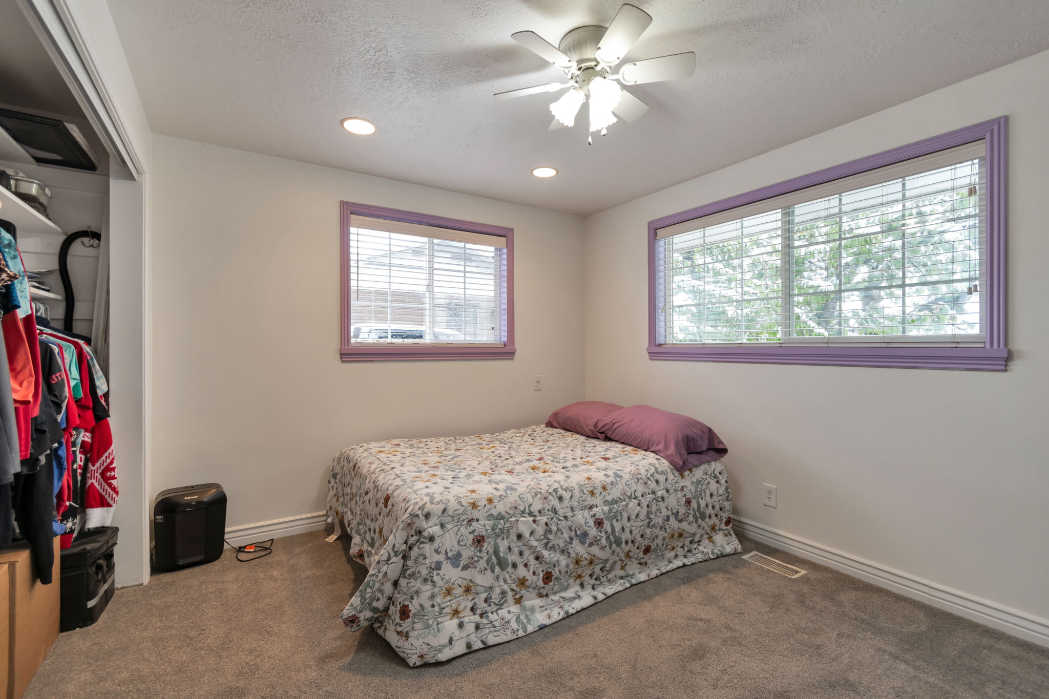 Carpeted room featuring a ceiling fan with integrated lighting, recessed lighting, and dual windows with blinds