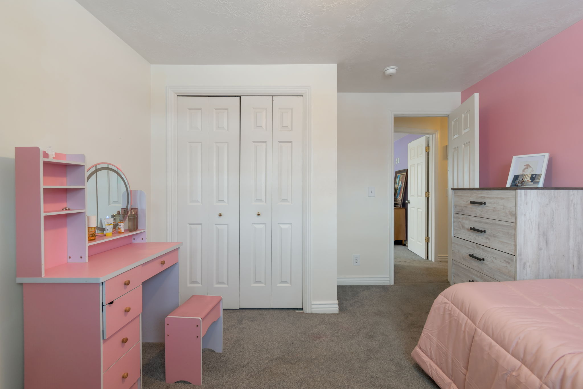 Room featuring bi-fold closet doors, wall-to-wall carpeting, and painted walls