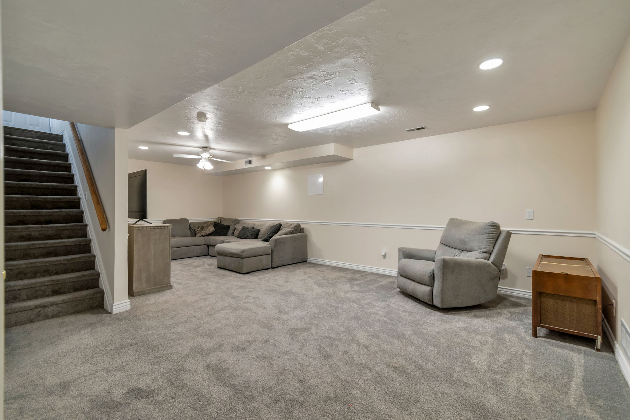 Carpeted recreation room featuring white baseboards, chair rail molding, and recessed lighting