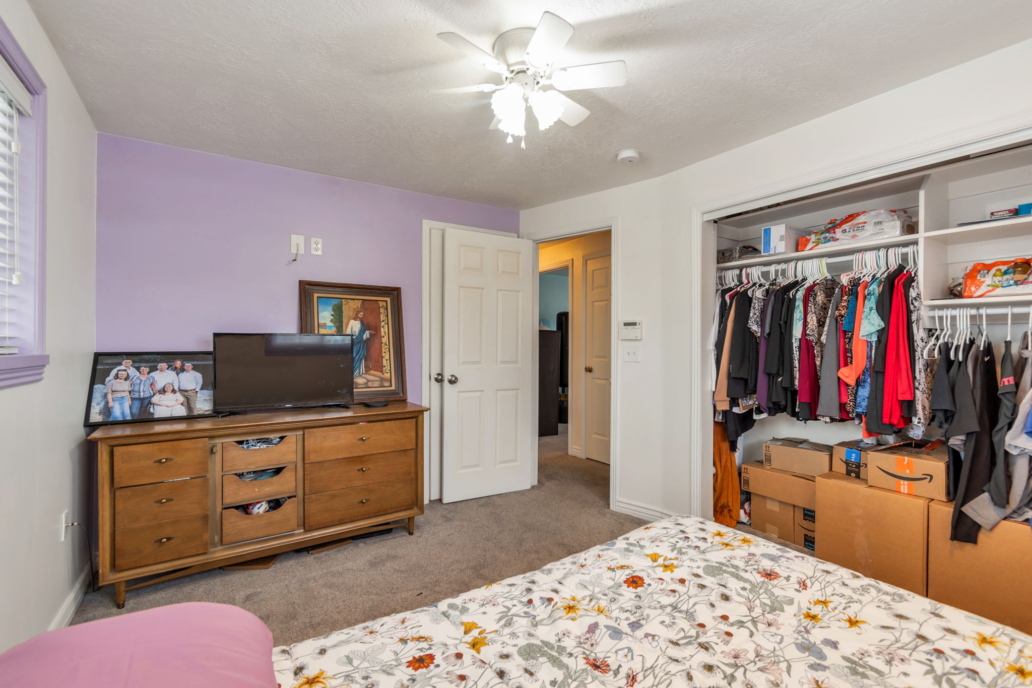 Bedroom with overhead ceiling fan, window with horizontal blinds, and a built-in closet featuring shelving and hanging space