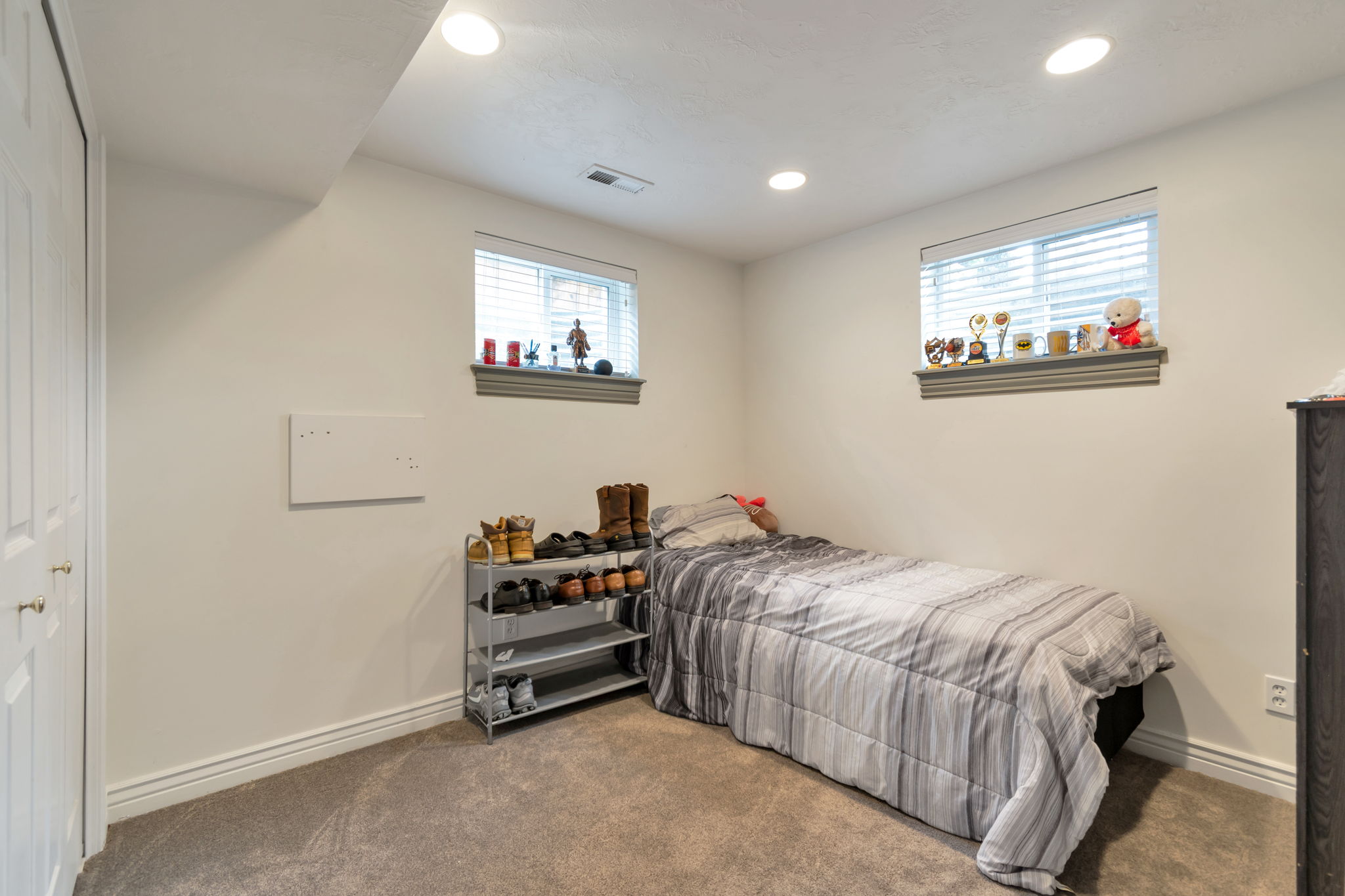 Carpeted room featuring recessed lighting, two windows with blinds, and white bi-fold closet doors
