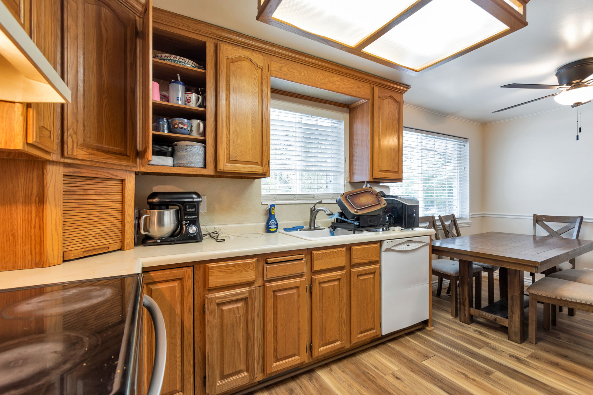 Kitchen featuring wood-finish flooring, wood cabinetry, white countertops, and a double window above the sink