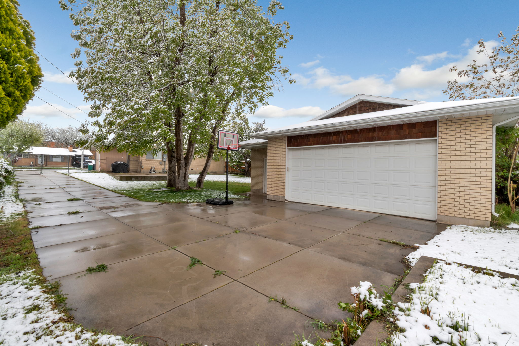 Two-car garage with a white panel door, light brick exterior, and decorative wood-finish siding