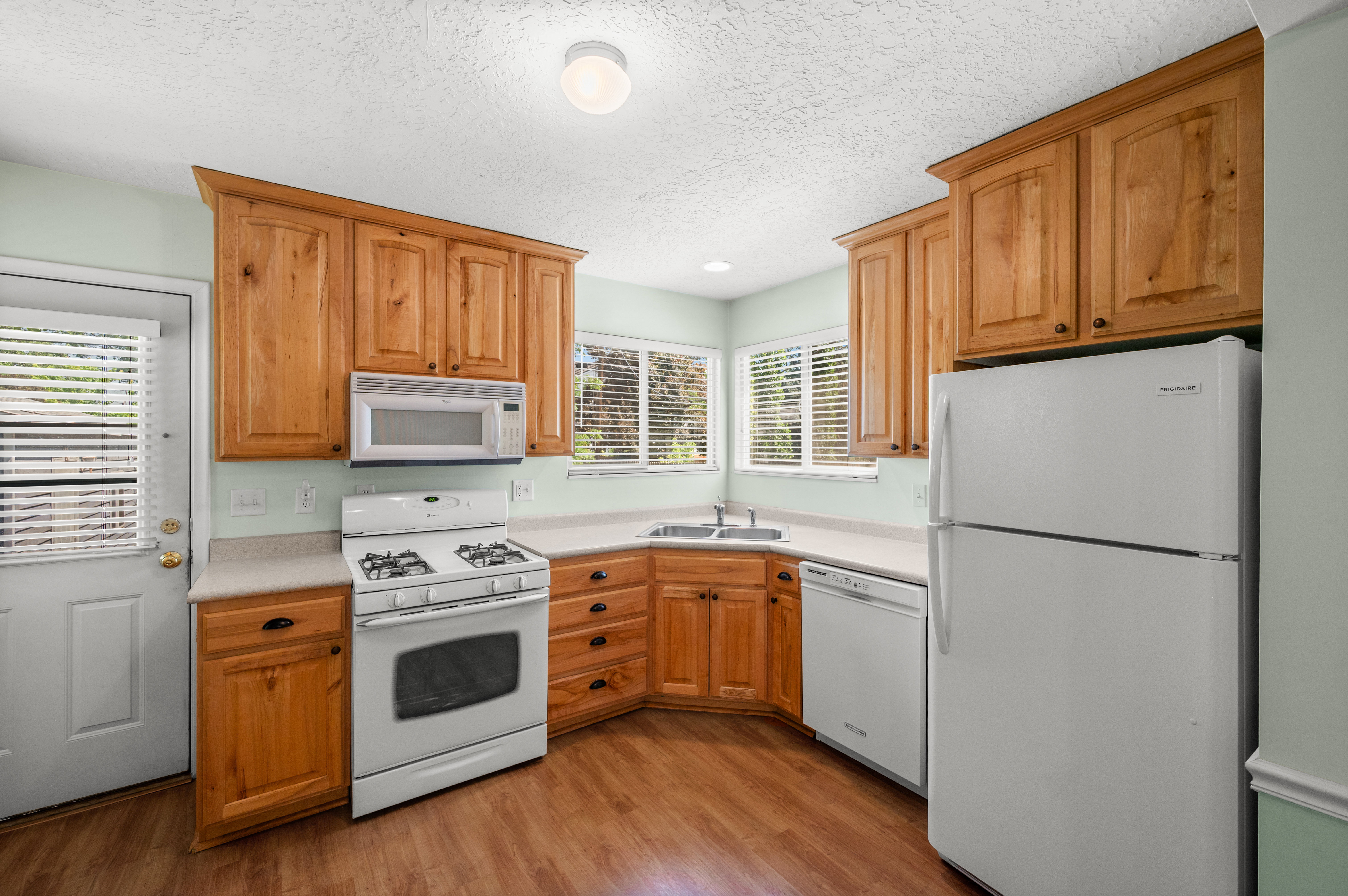 Kitchen featuring wood-finish cabinetry, white appliances, and light-toned countertops