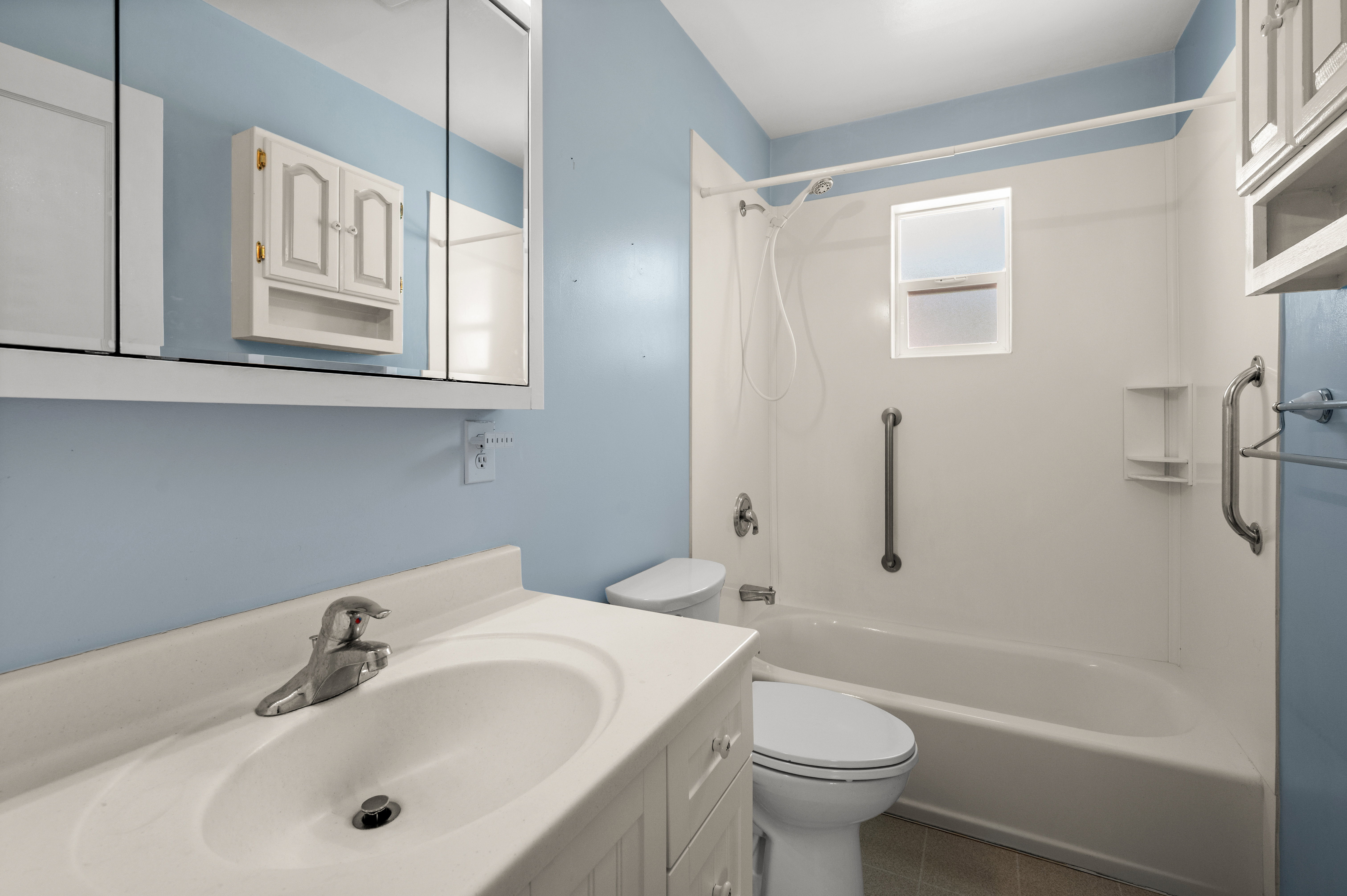 Bathroom featuring a white vanity with integrated sink, chrome faucet, and mirrored medicine cabinet