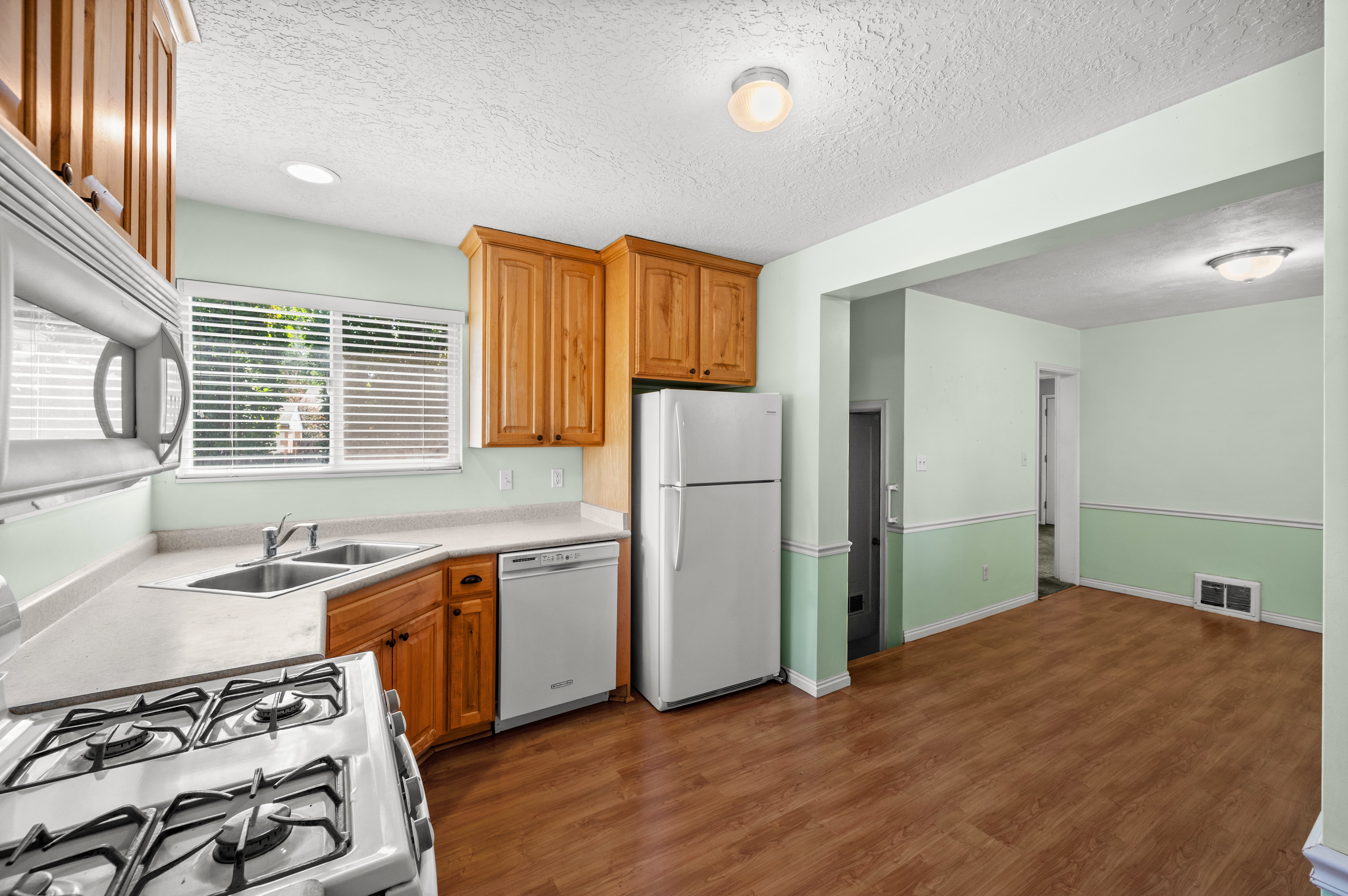 Kitchen featuring wood cabinetry, a dual basin stainless steel sink, and light-toned countertops