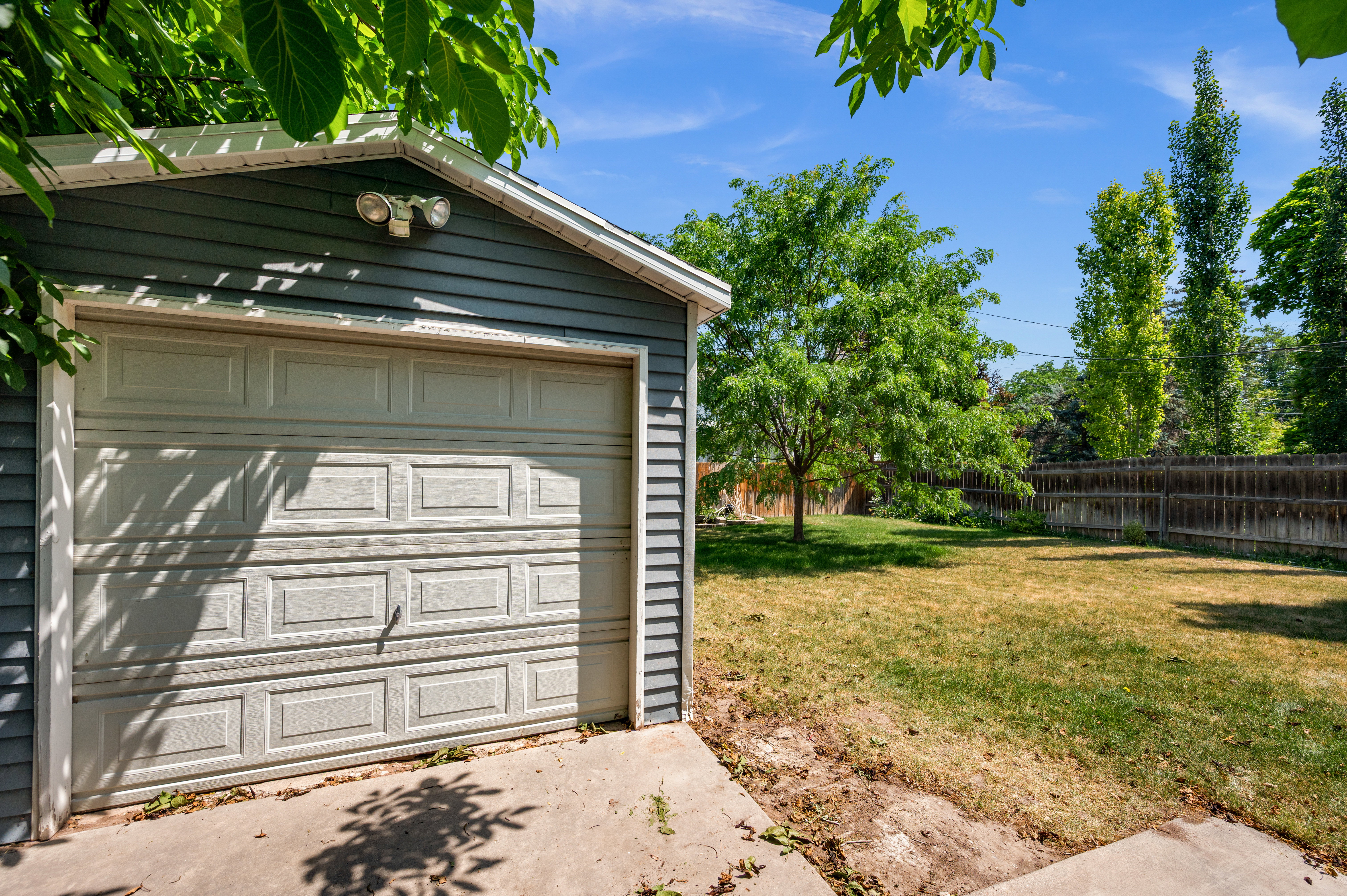 Detached garage featuring panel siding and a roll-up door, complemented by a security light fixture