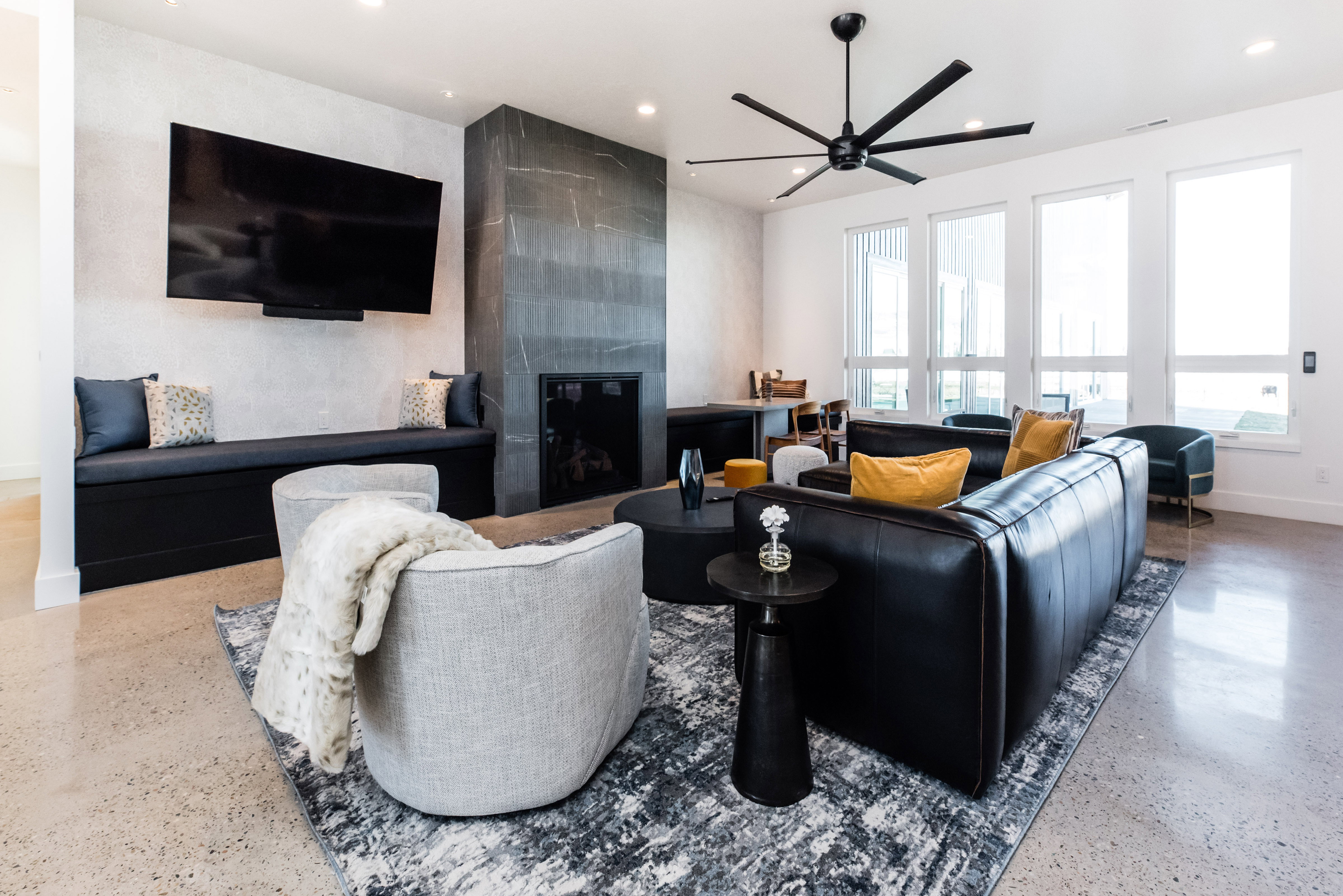 Open-concept living space featuring polished concrete flooring, a contemporary ceiling fan, and multiple vertical windows