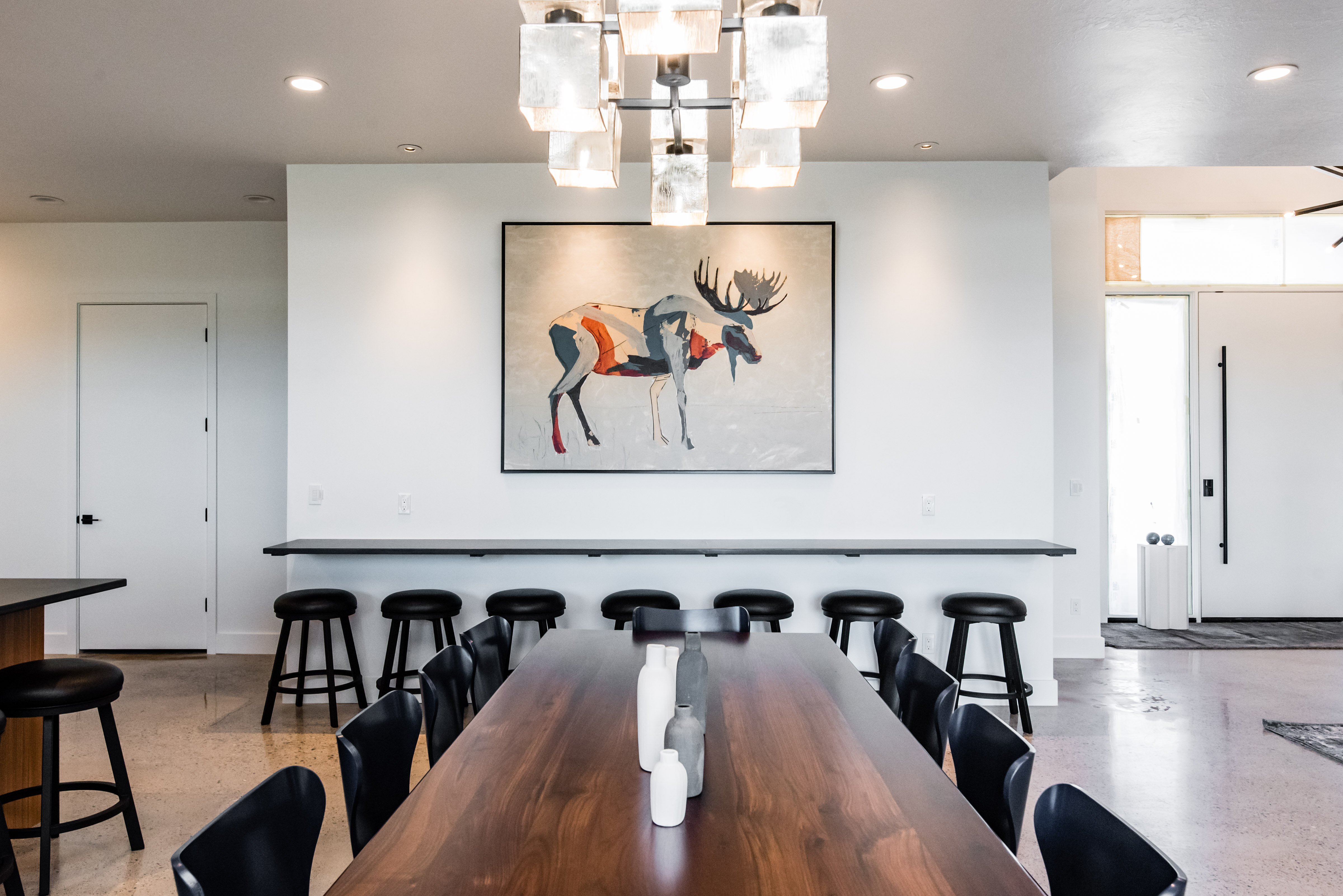 Spacious dining area featuring a modern chandelier, wood-finish flooring, and a built-in counter with seating