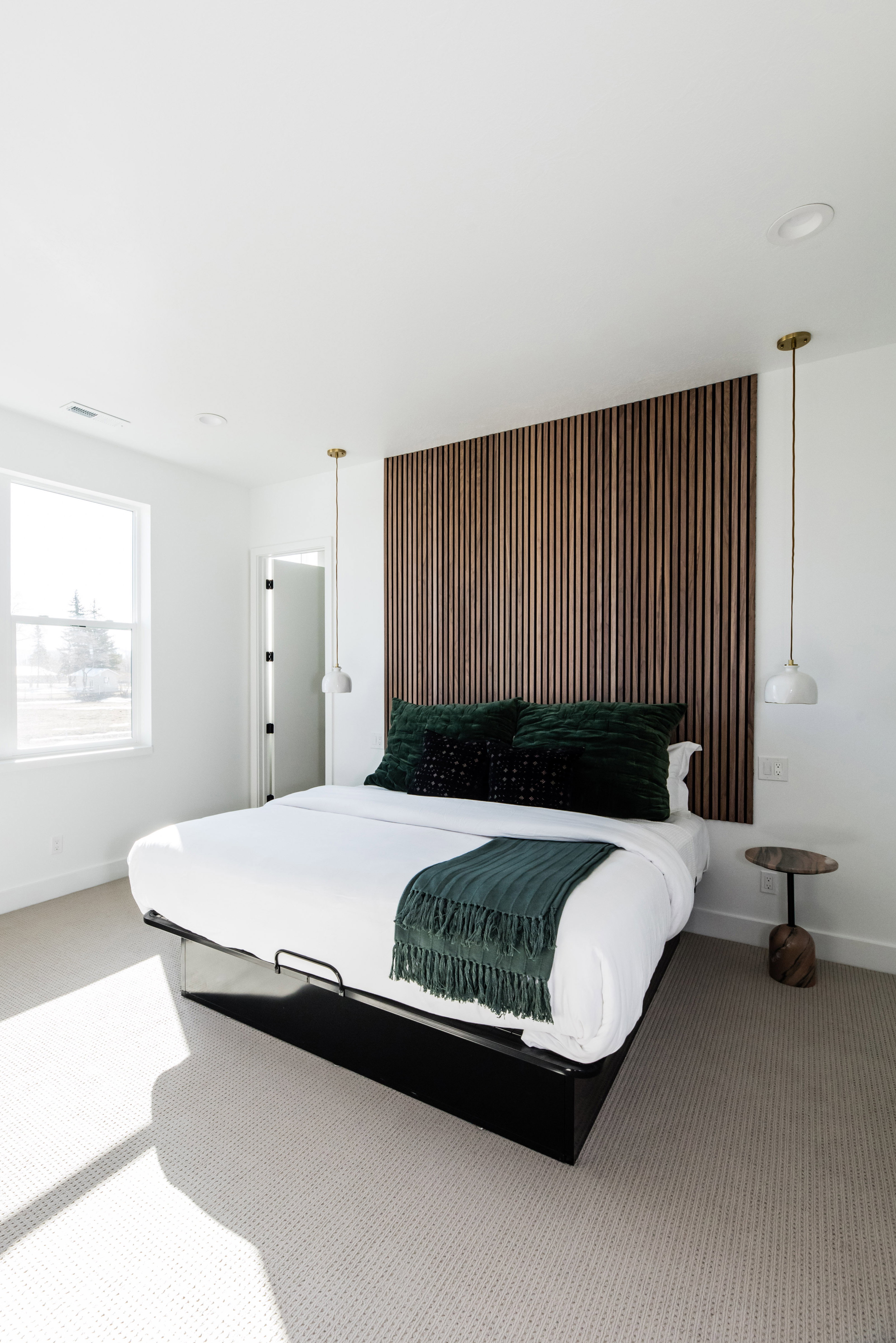 Bedroom featuring a slatted wood accent wall, dual pendant lights, recessed lighting, and a large window