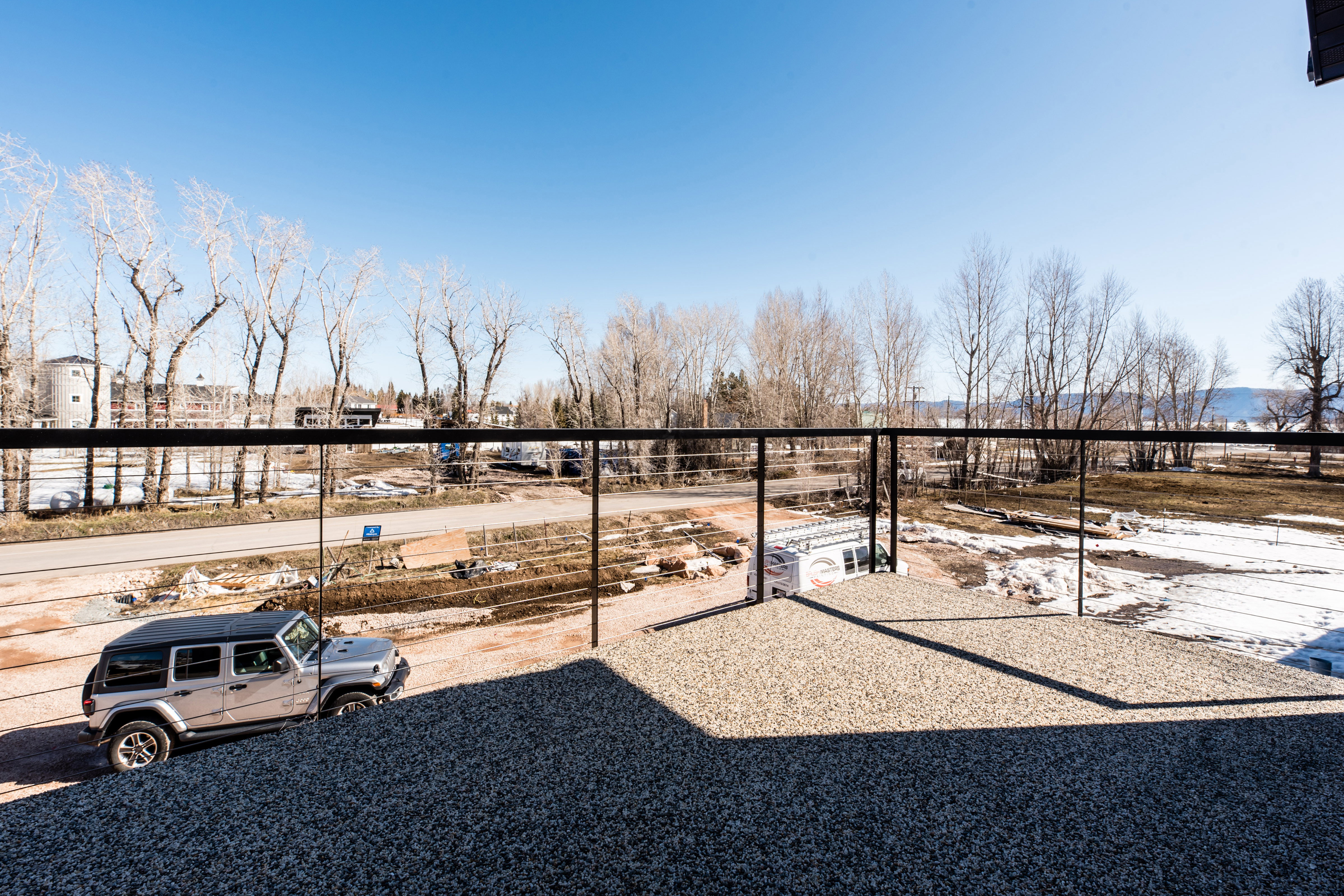 Outdoor gravel-finished deck featuring black metal railings with wire infill