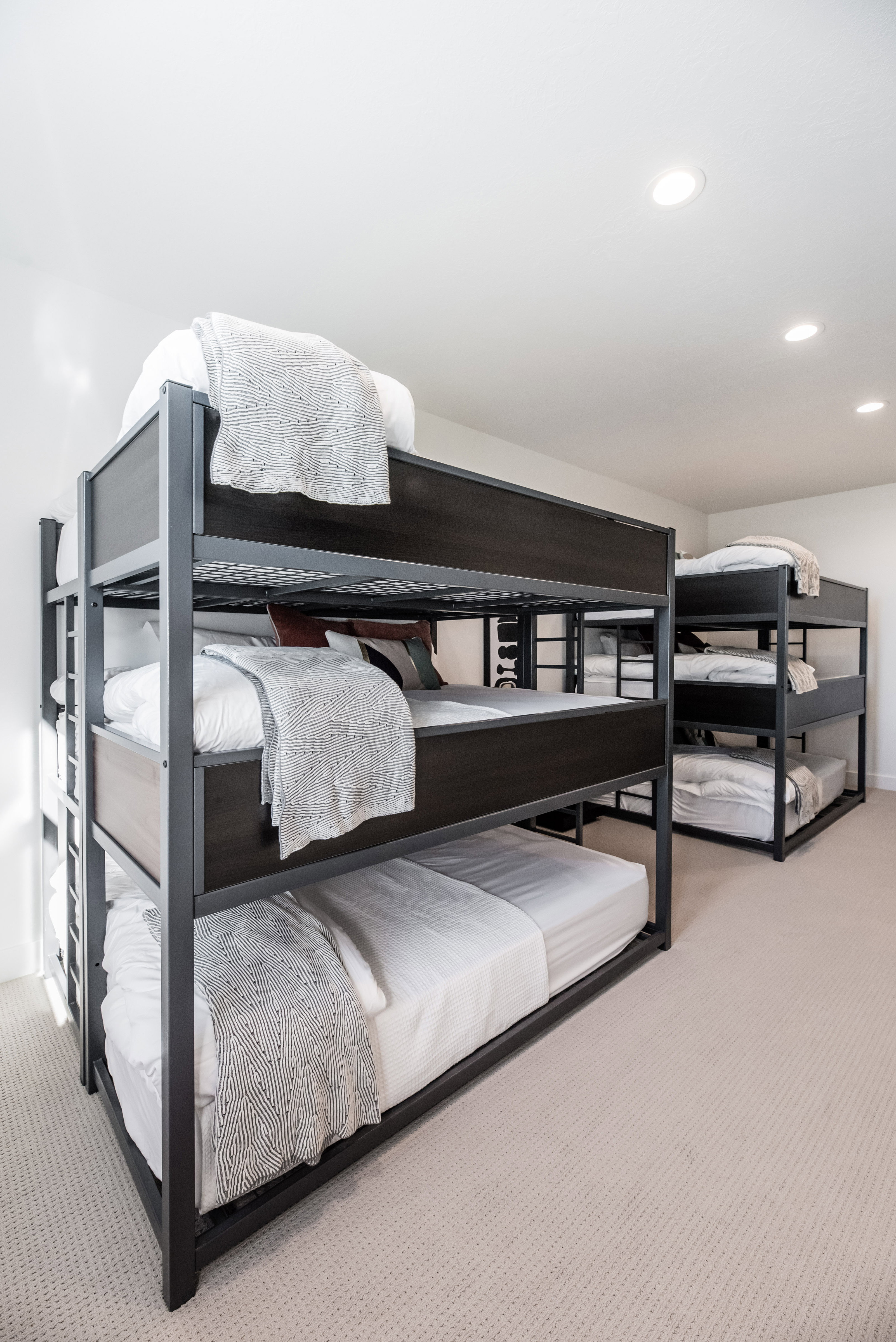 Spacious room featuring two dark-toned triple bunk beds with minimalist frames