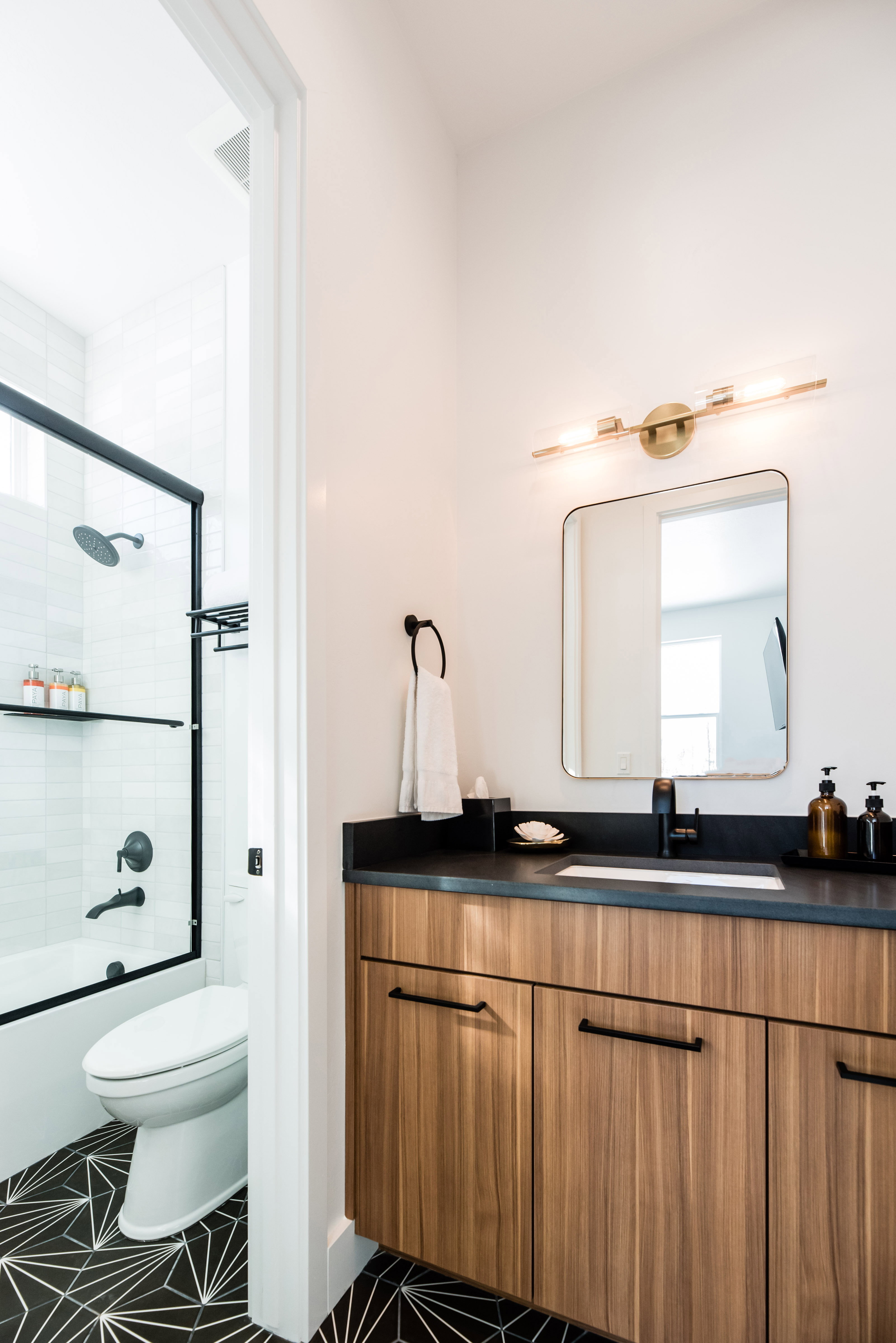 Contemporary bathroom featuring a floating wood-finish vanity with a dark countertop and integrated sink