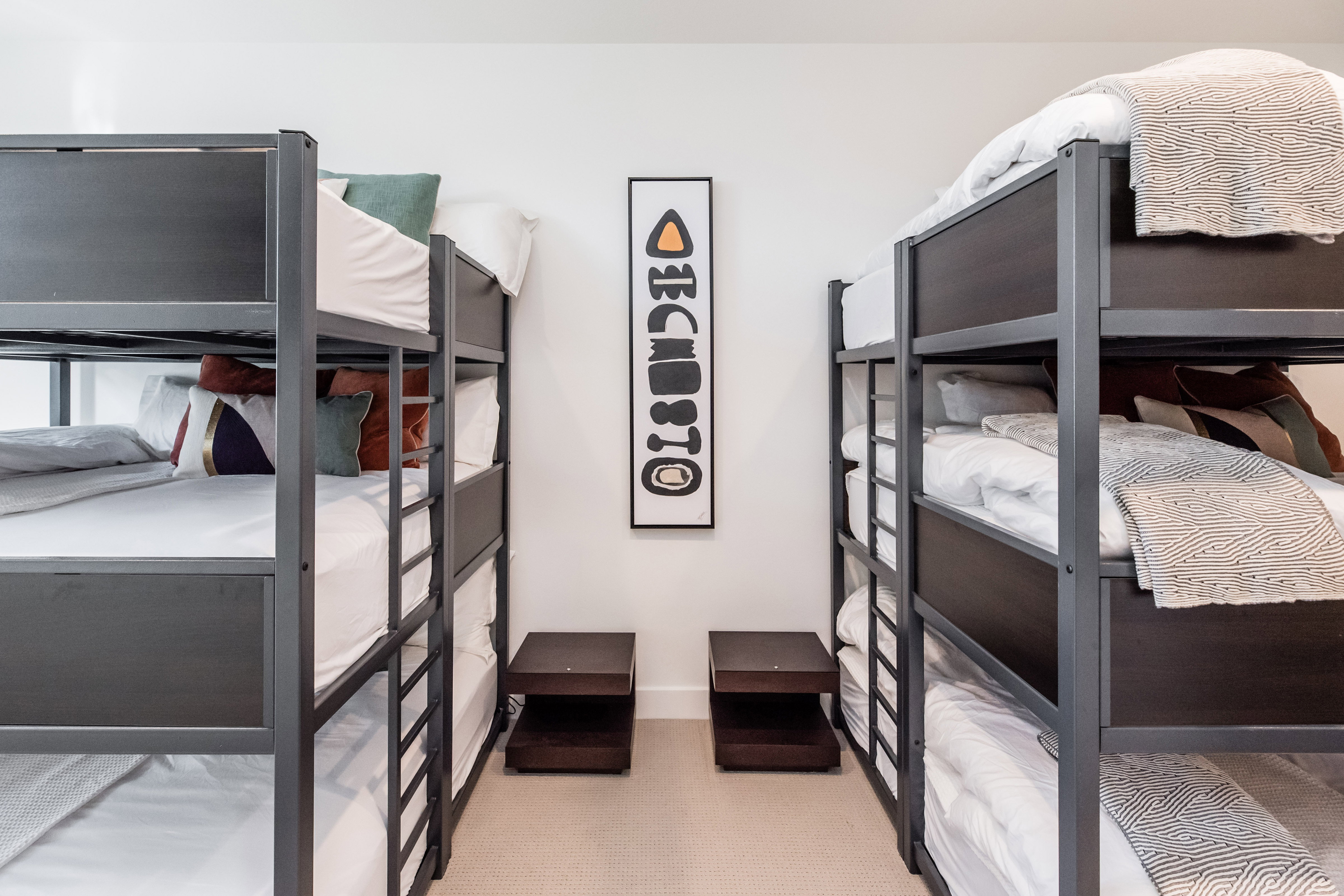 Room featuring two sets of triple bunk beds with metal frames, plush carpeting, and recessed lighting