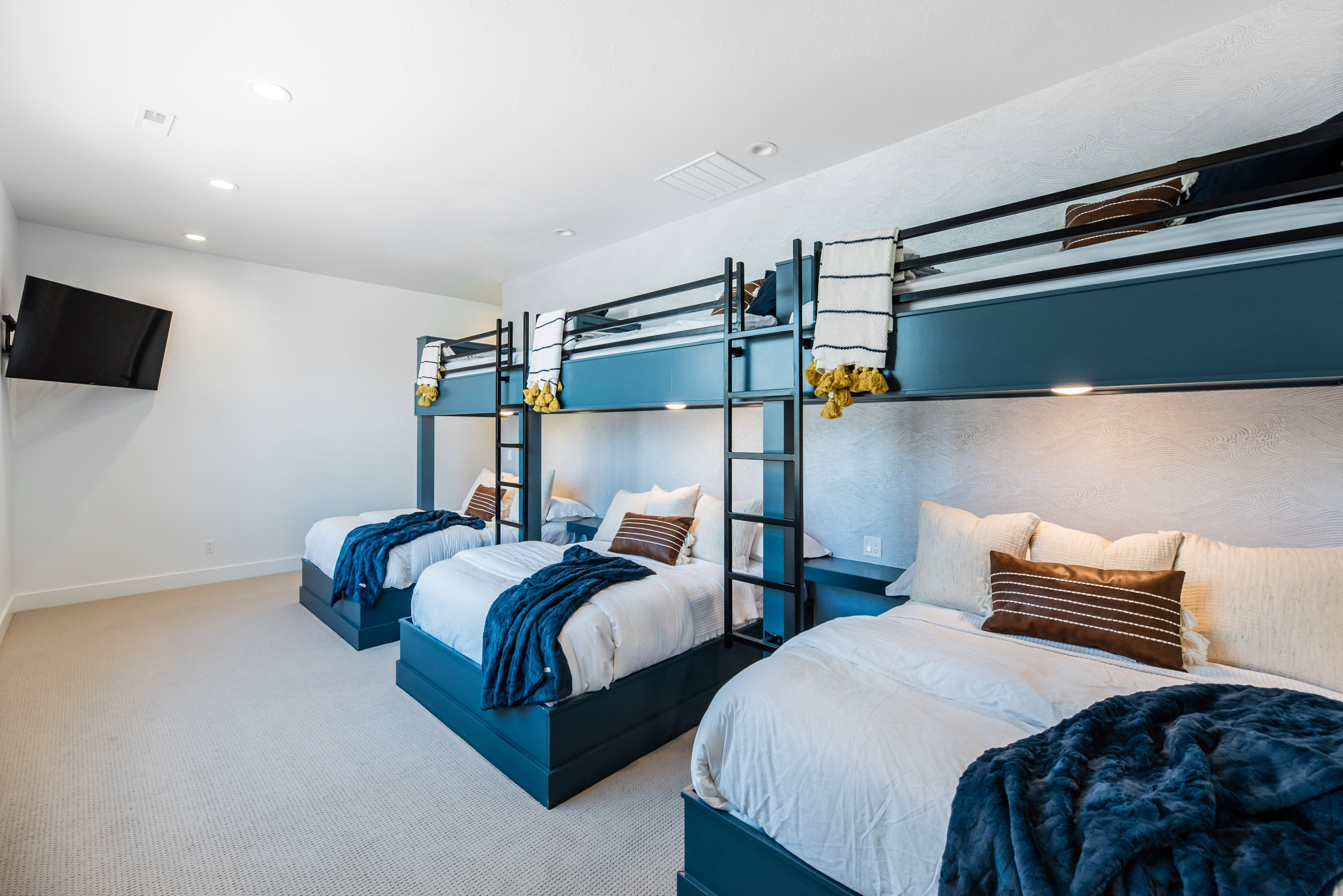 Bedroom featuring custom built-in bunk beds with integrated lighting, a wall-mounted television, recessed ceiling lights, and light-toned carpeting