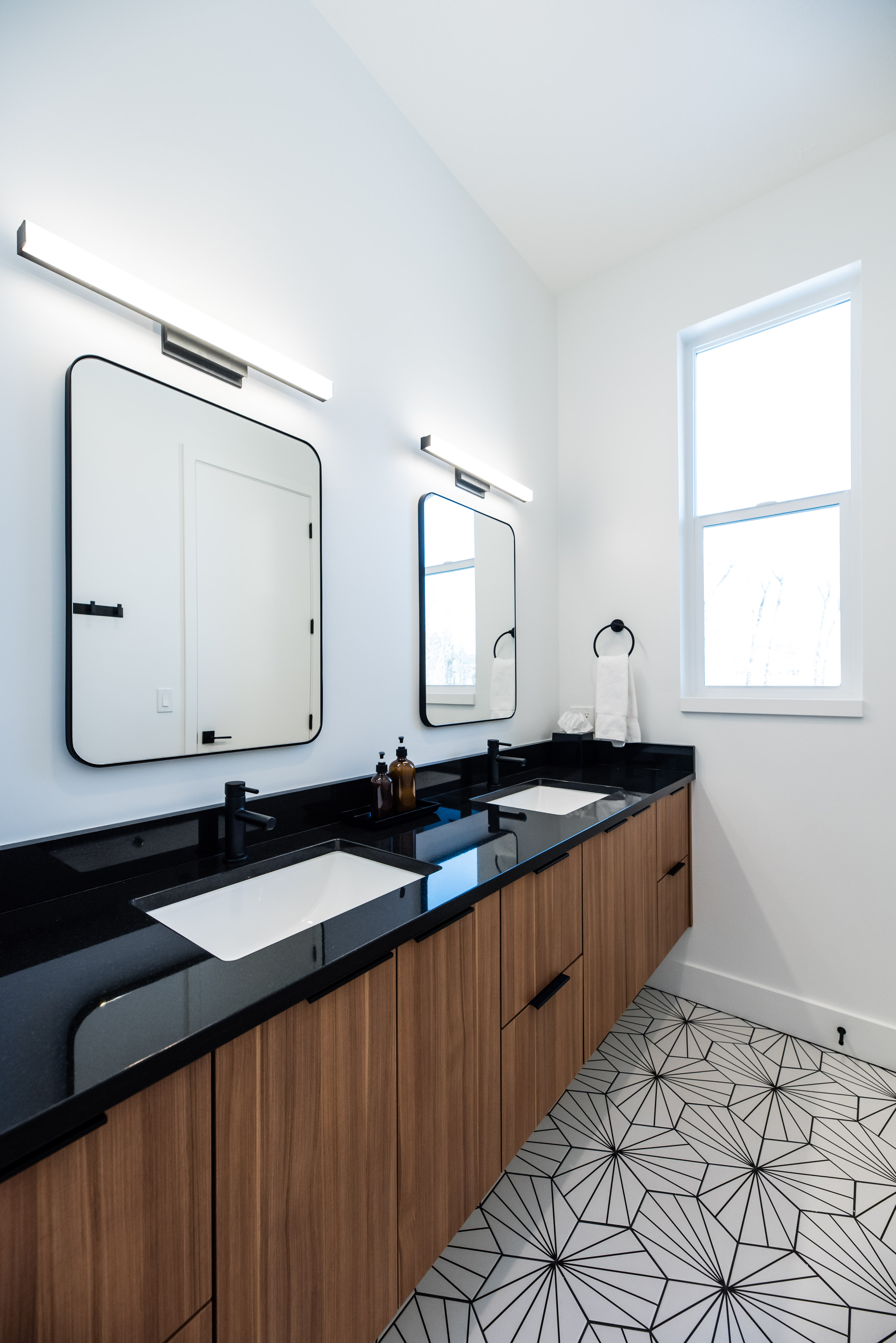 Floating double vanity with wood-finish cabinetry, black countertops, and integrated rectangular sinks