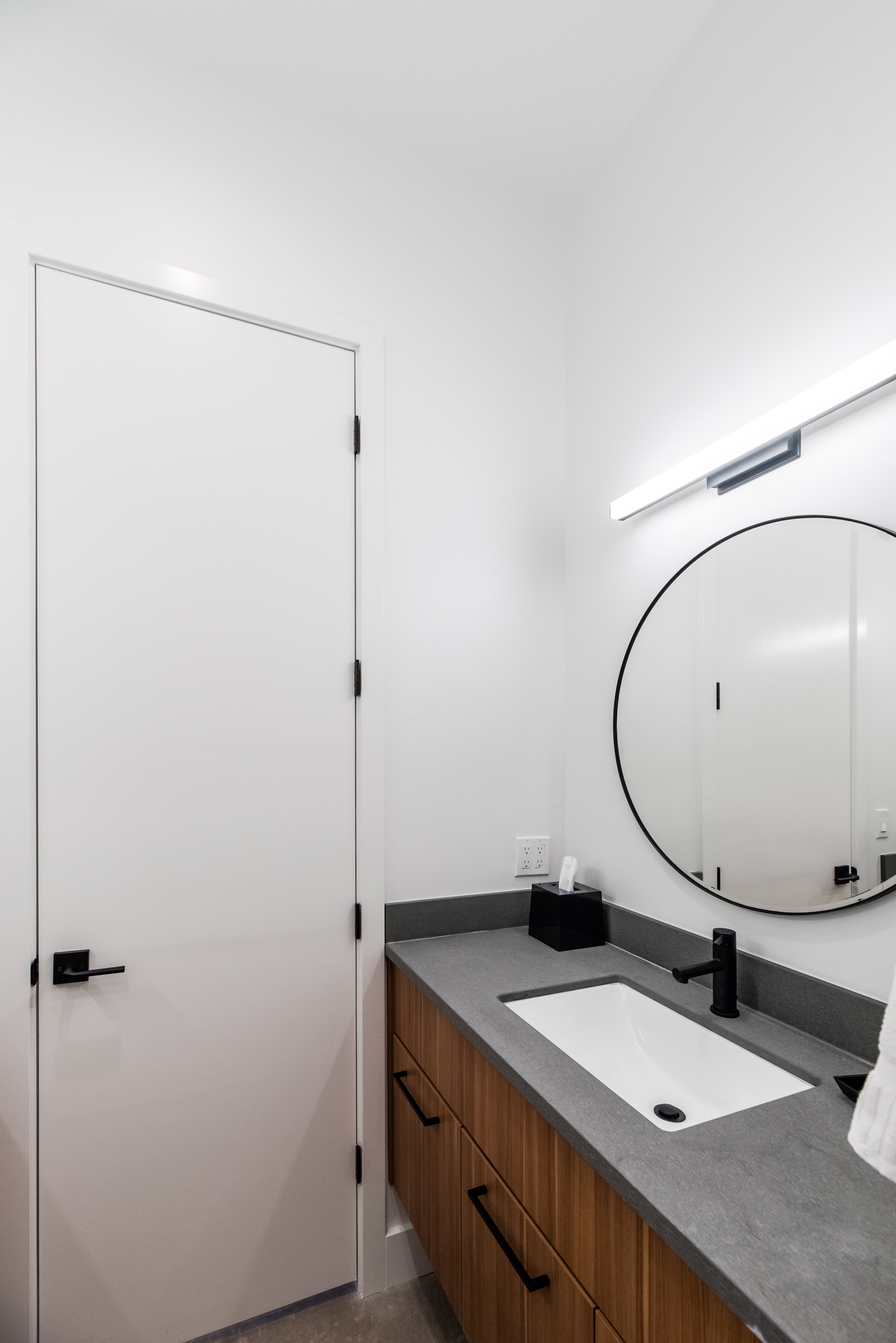 Contemporary bathroom featuring a floating wood-finish vanity with a dark countertop, an integrated rectangular sink, and a matte black faucet