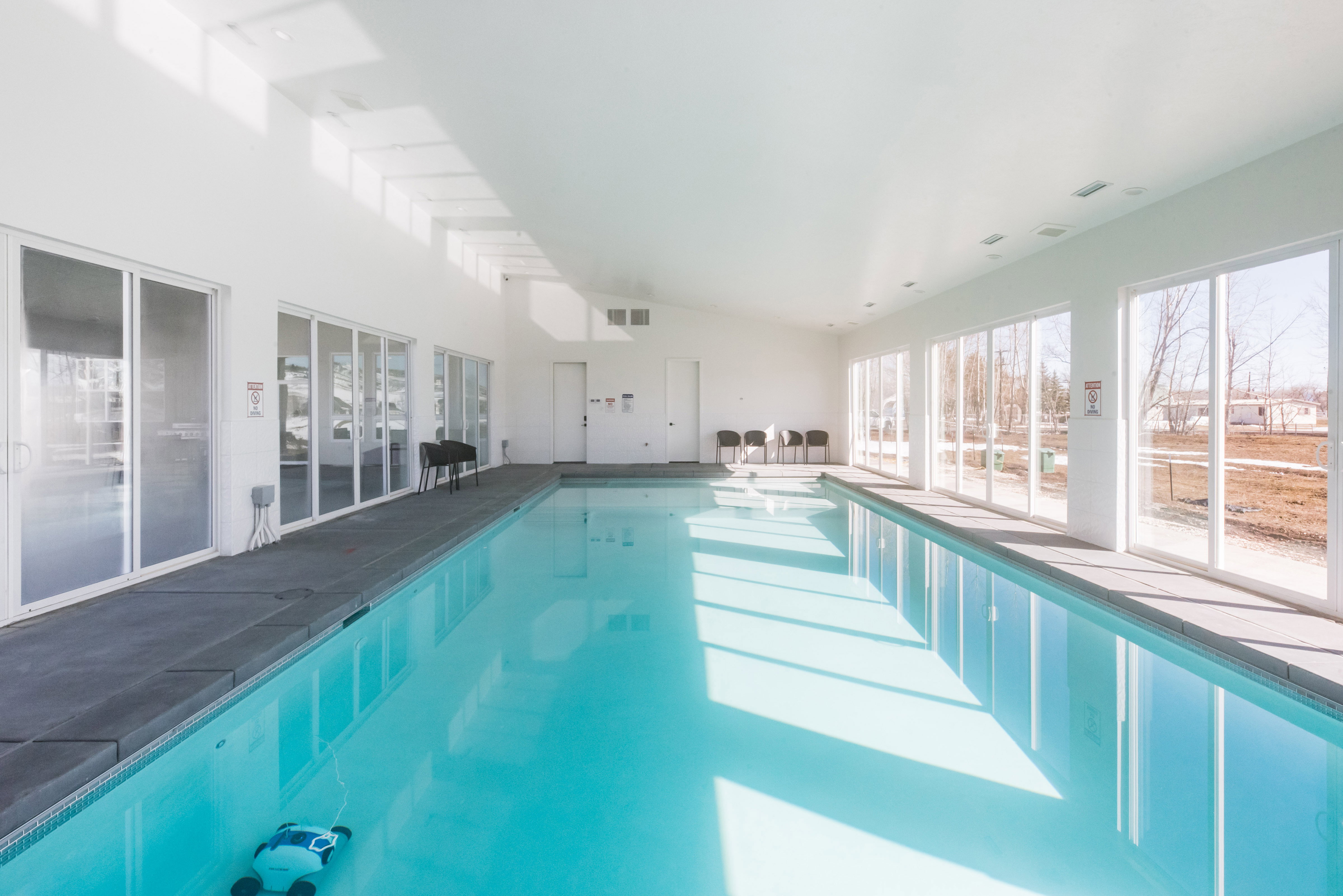 Indoor swimming pool with white walls, a vaulted ceiling, and dark perimeter decking