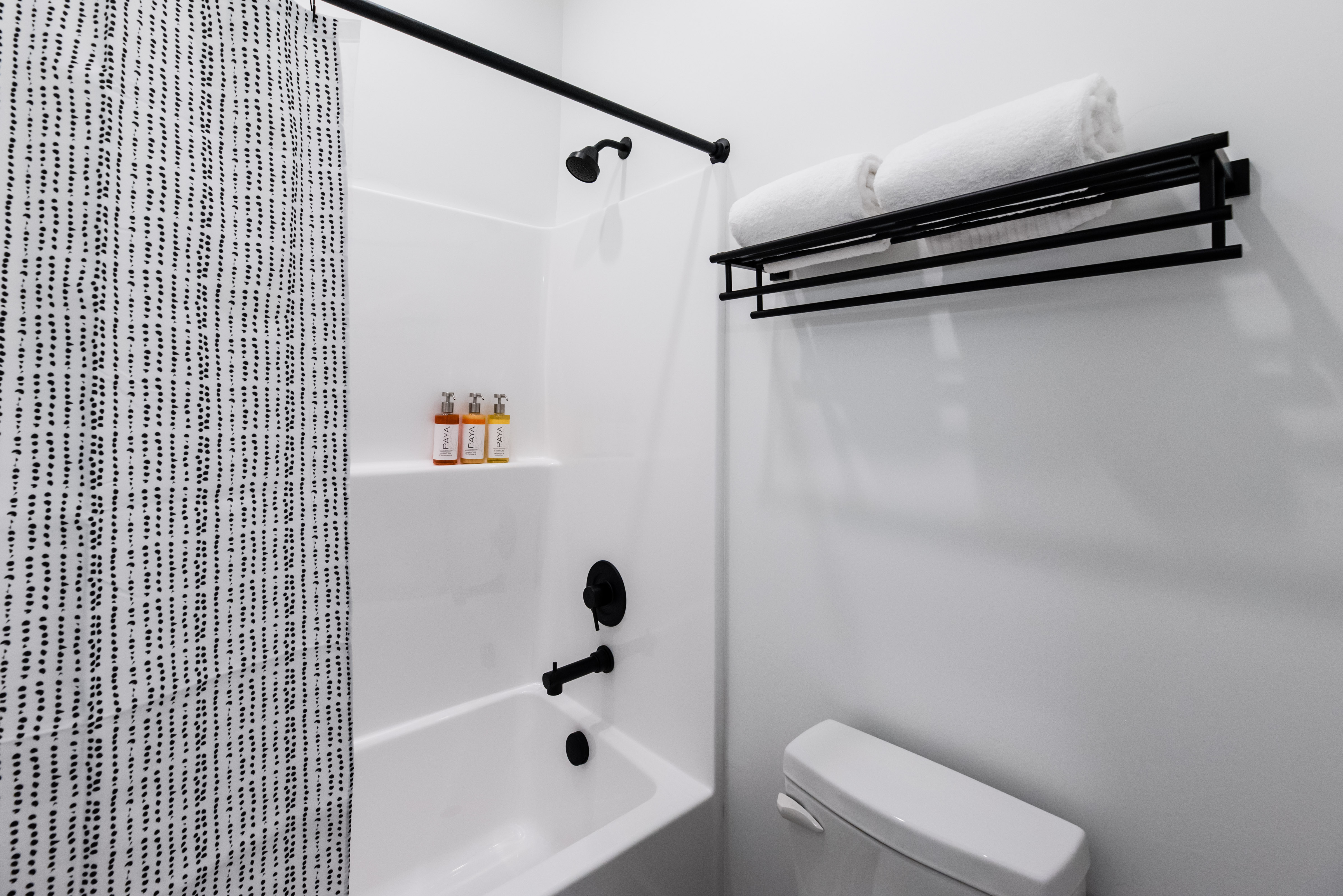 Full white bathtub with black fixtures, including a shower head, faucet, and shower rod