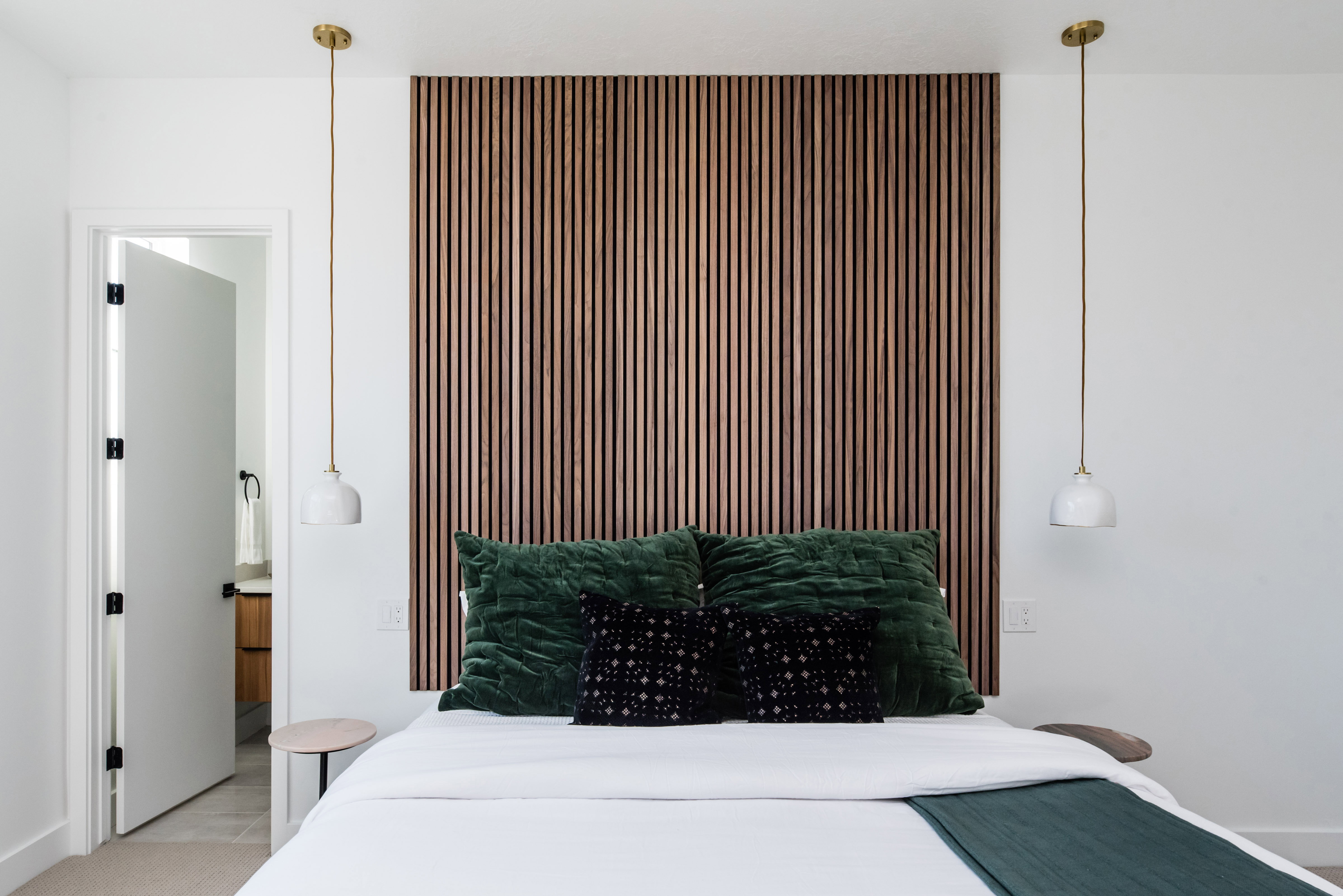 Accent wall with vertical wood paneling, featuring two brass-finished pendant lights with white shades