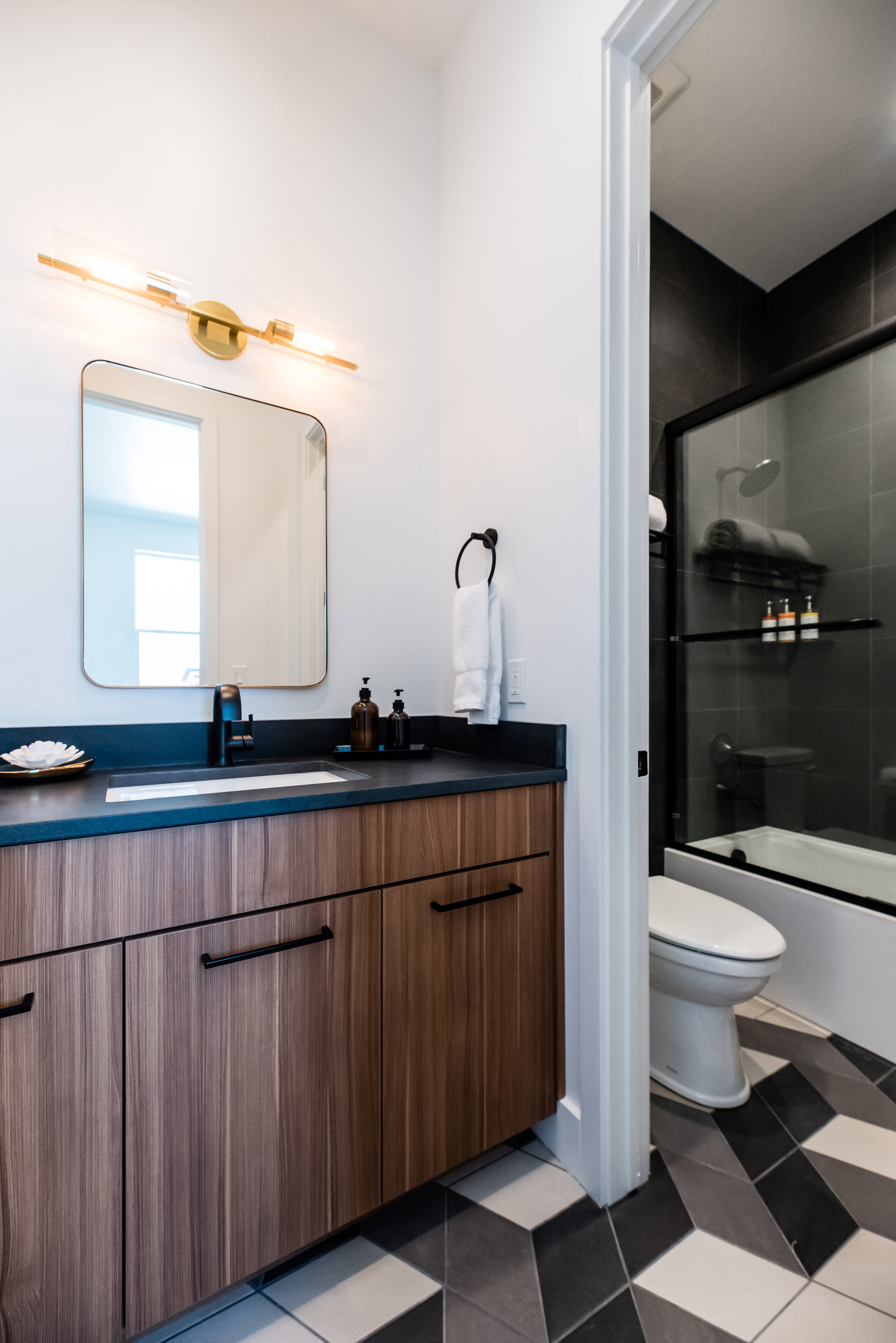 Bathroom vanity featuring wood-finish cabinetry, a dark countertop with an integrated sink, and matte black hardware