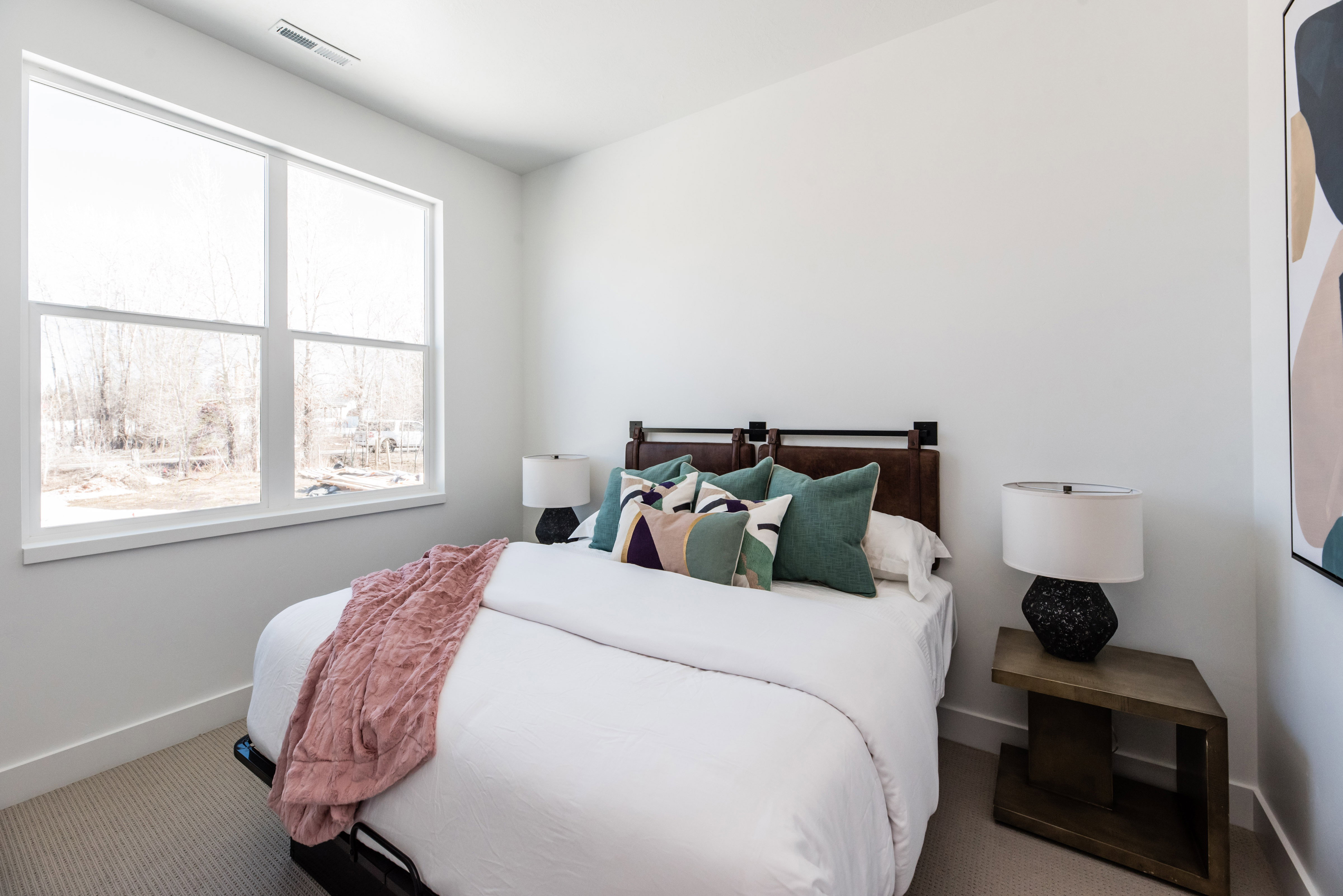 Carpeted bedroom with a large window, white walls, and a dark wood headboard