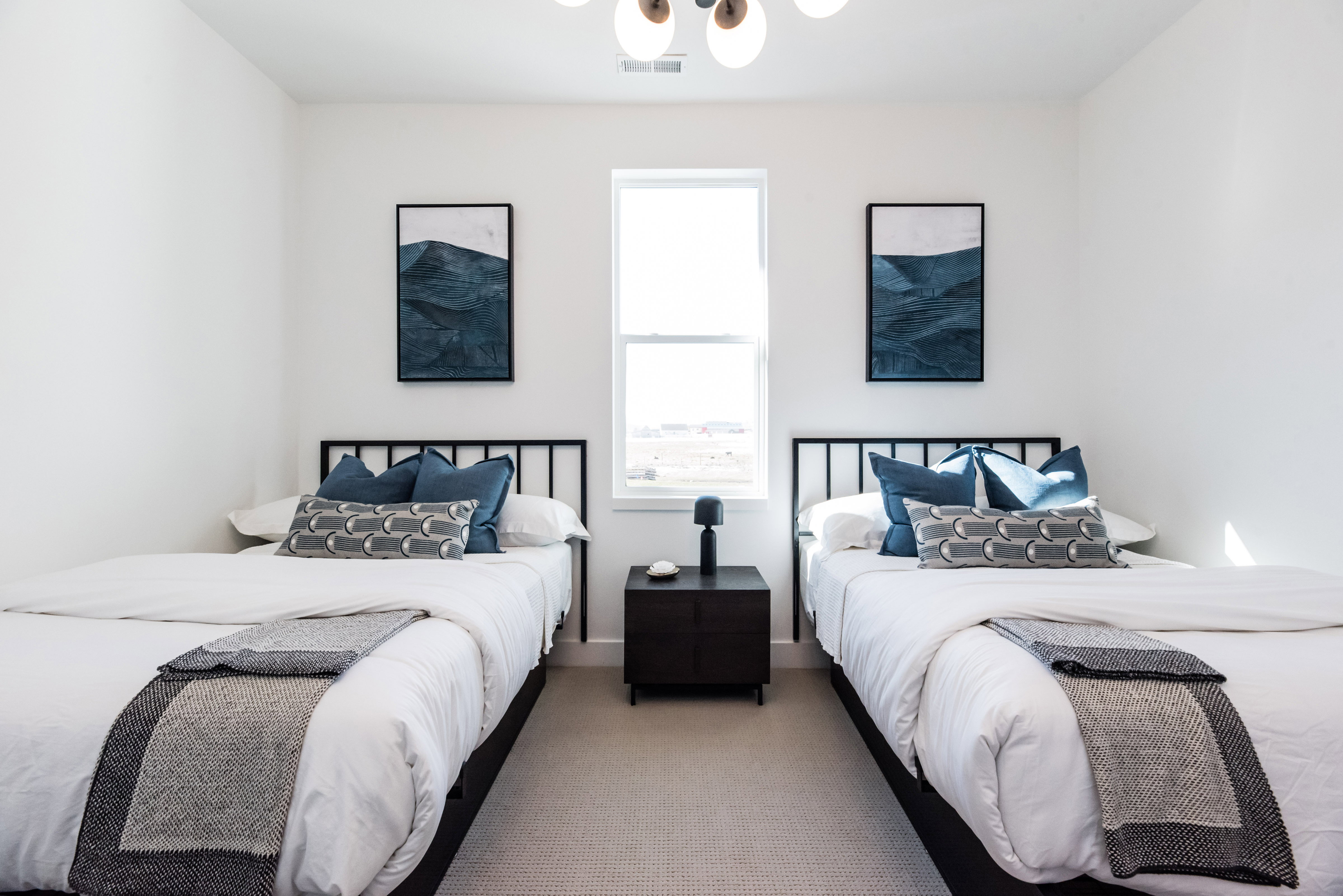 Bright room with a central window, two framed art pieces, and a contemporary ceiling light fixture