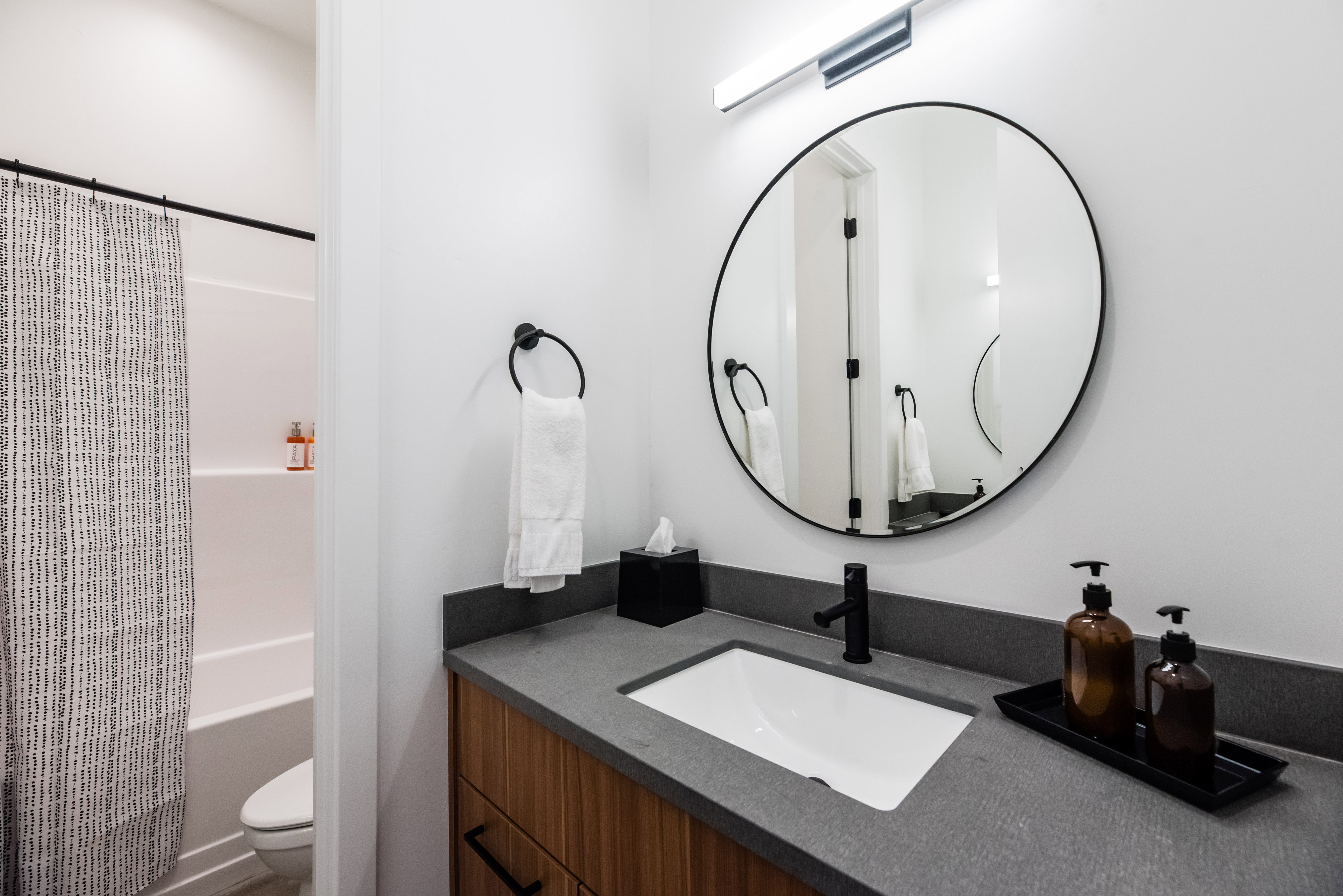 Bathroom featuring a wood-finish vanity with a built-in rectangular sink, a dark countertop, and matte black fixtures
