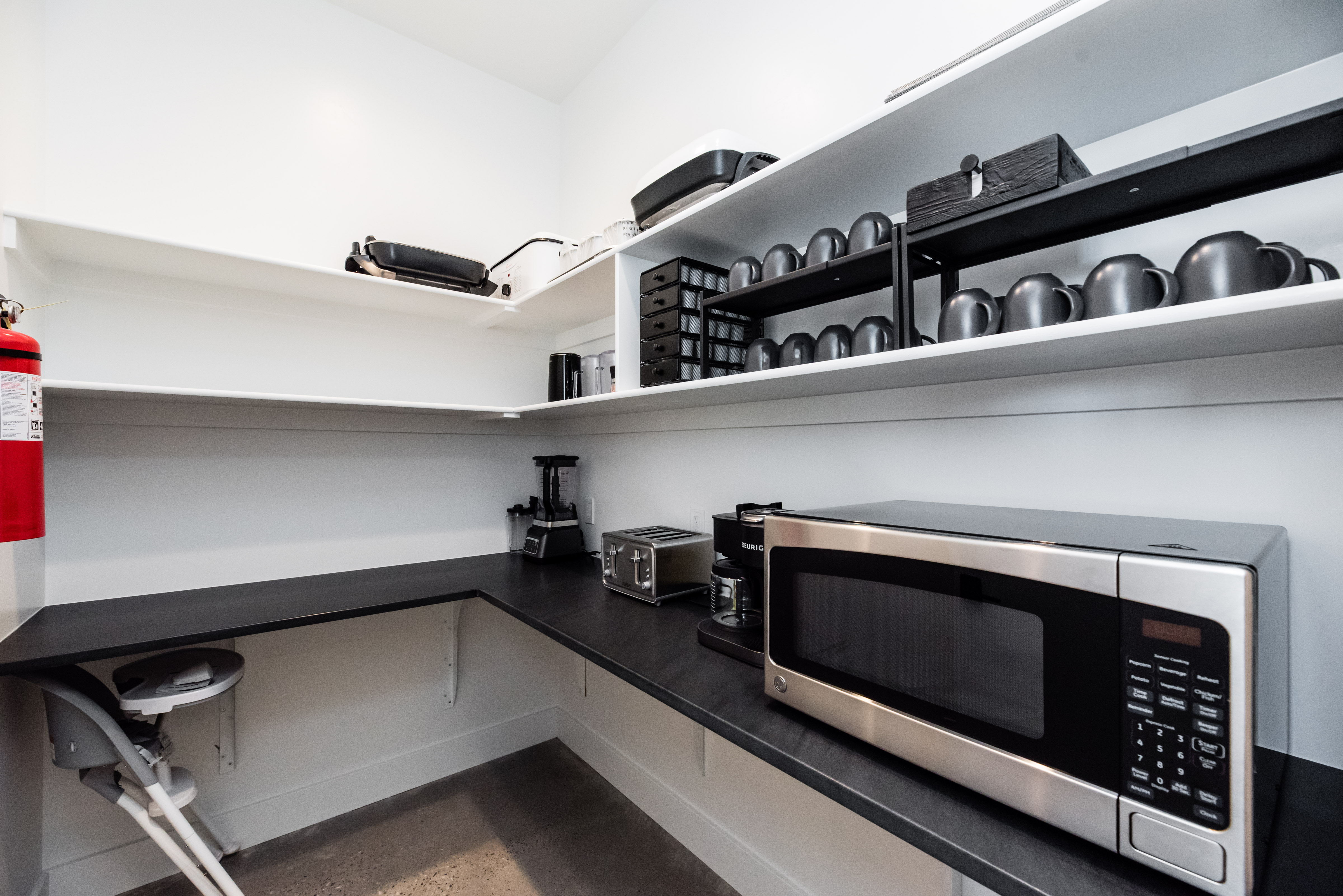 Spacious pantry featuring white walls, wrap-around black countertops, and multiple levels of white shelving