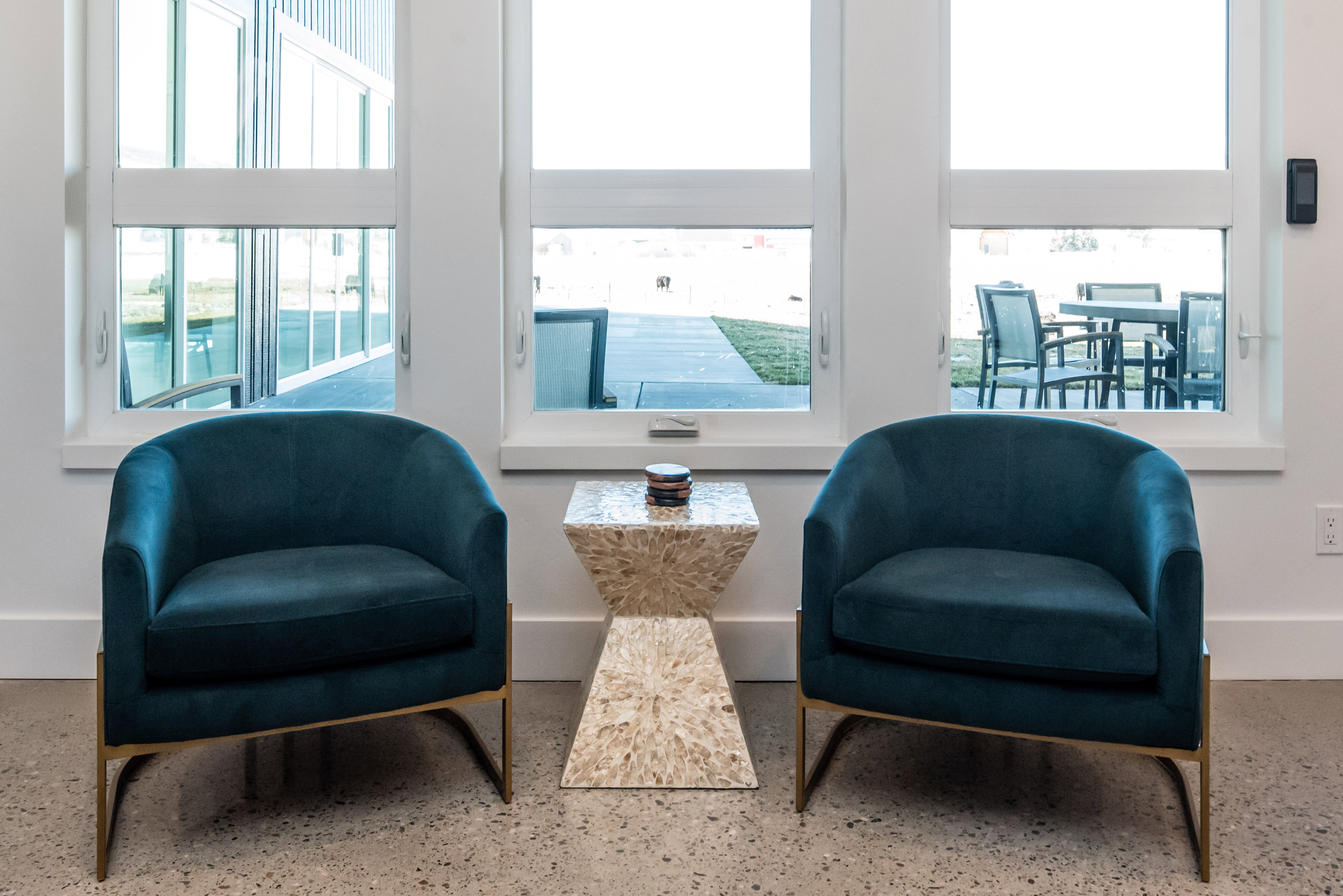 Bright interior space featuring three large windows, white trim, and a concrete floor