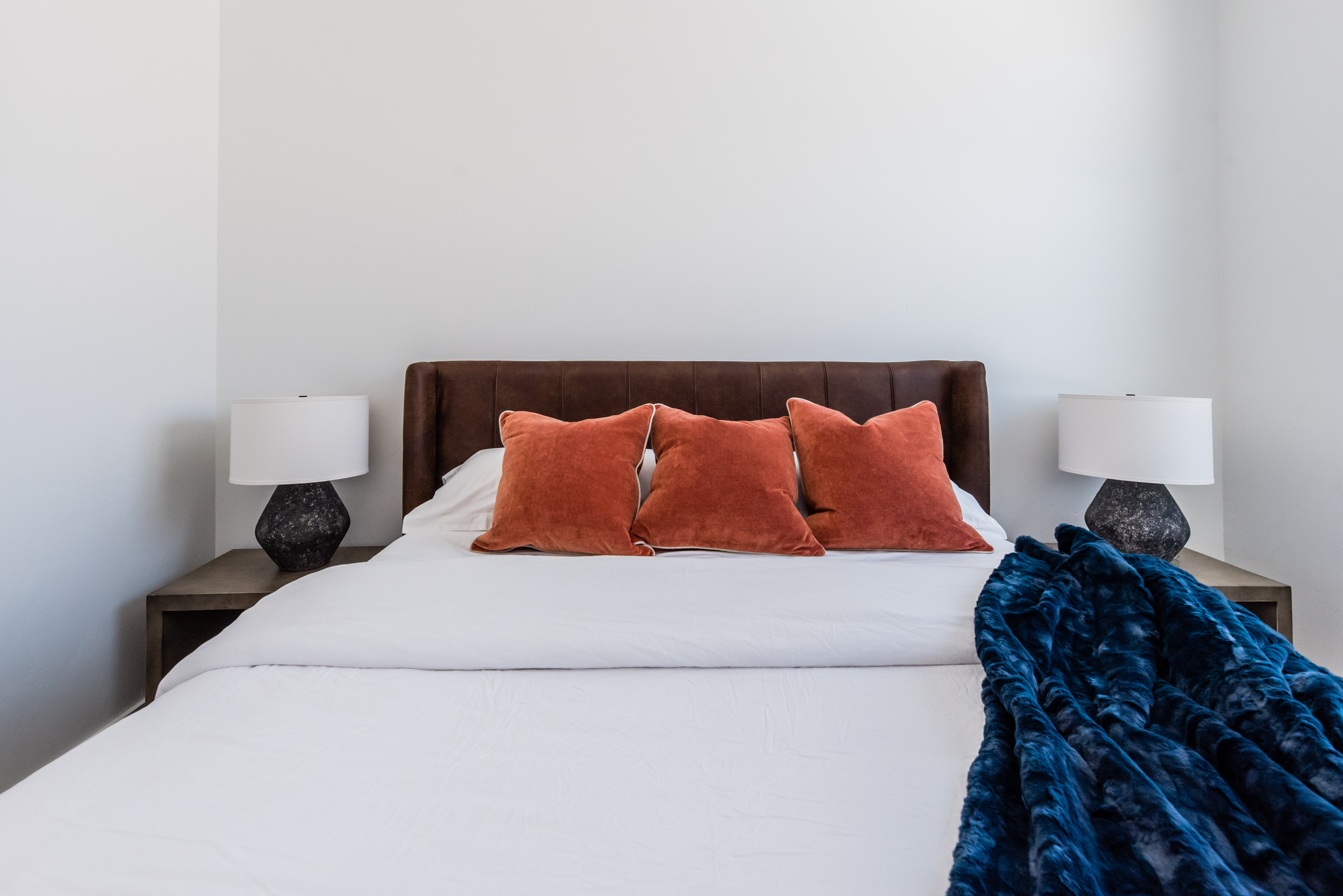 Bedroom featuring a leather upholstered headboard, clean white walls, and two integrated bedside tables with lamps