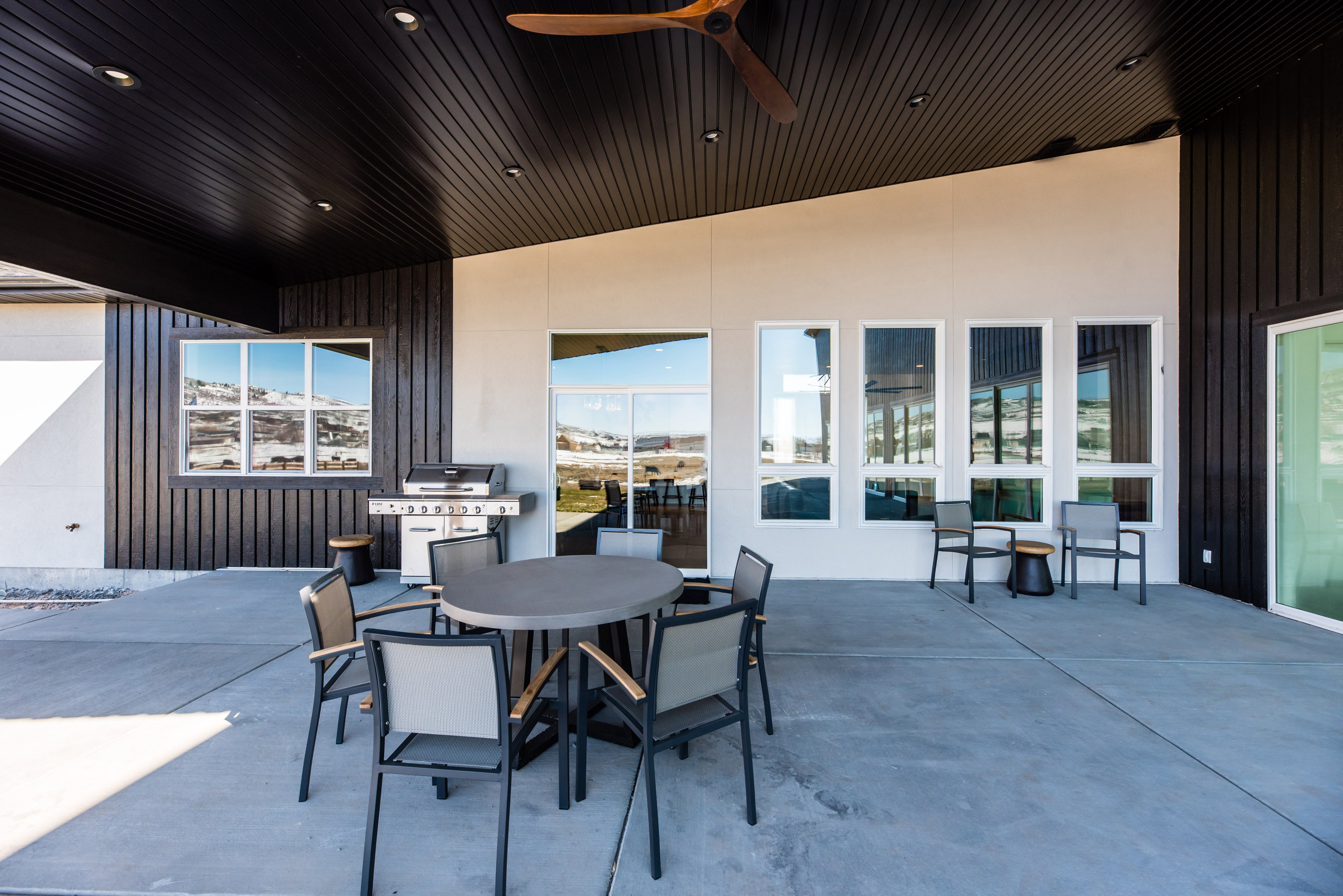Expansive outdoor patio featuring concrete flooring and a dark wood-finish ceiling with recessed lighting