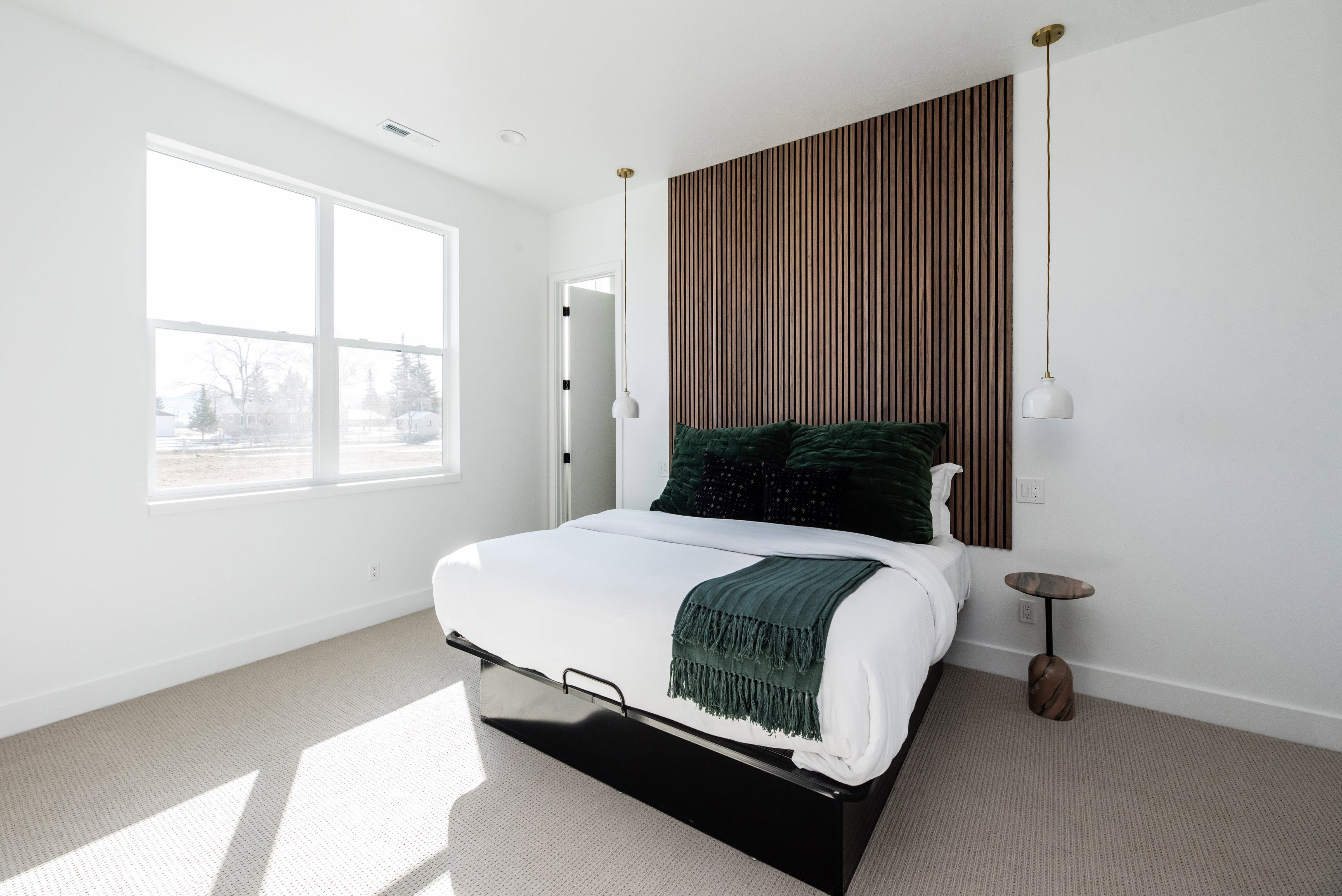 Bedroom featuring a wood slat accent wall, large picture window, recessed lighting, and soft carpet flooring