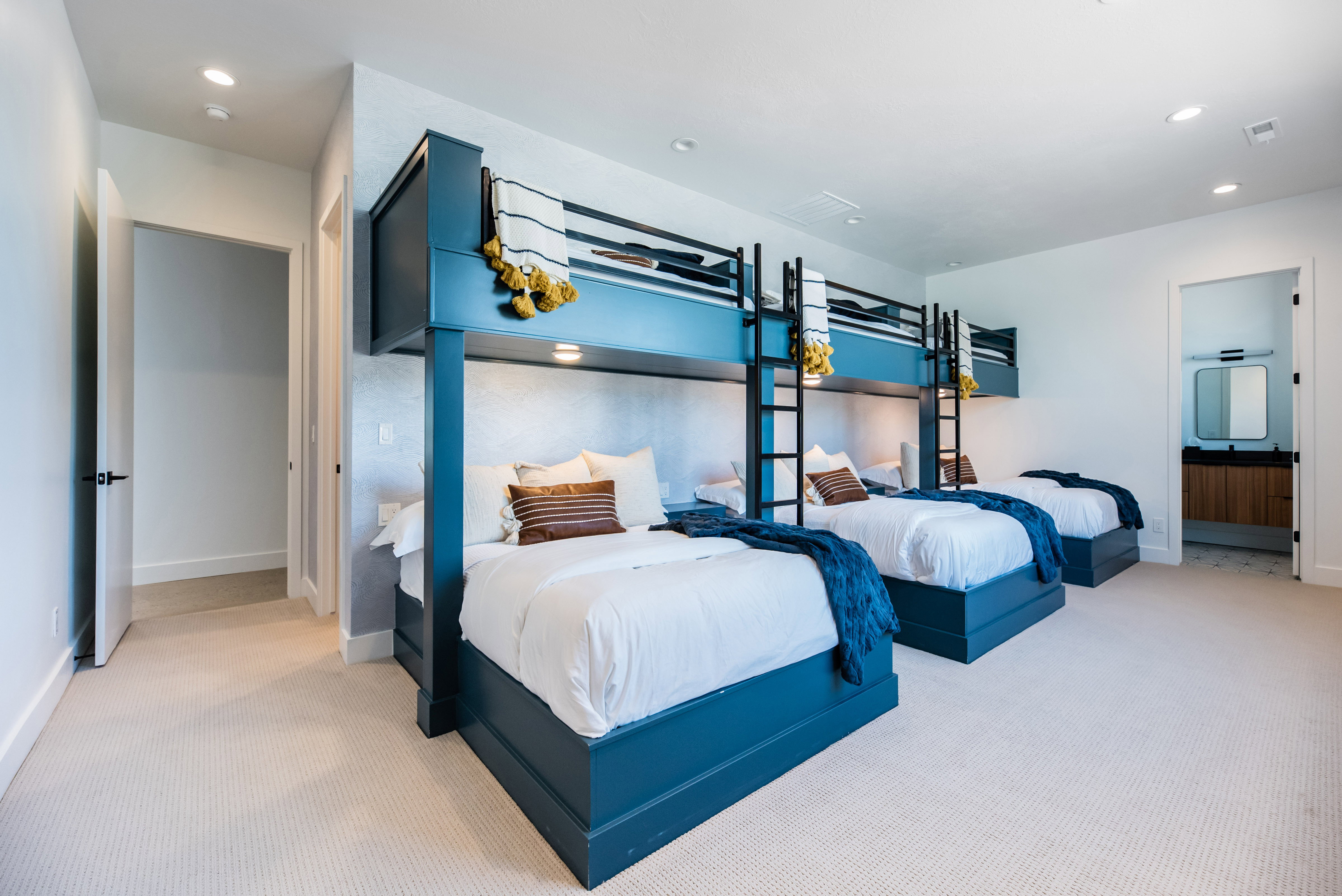 Custom built-in bunk beds with individual lighting fixtures, light-toned carpeting, recessed ceiling lighting, and crisp white walls