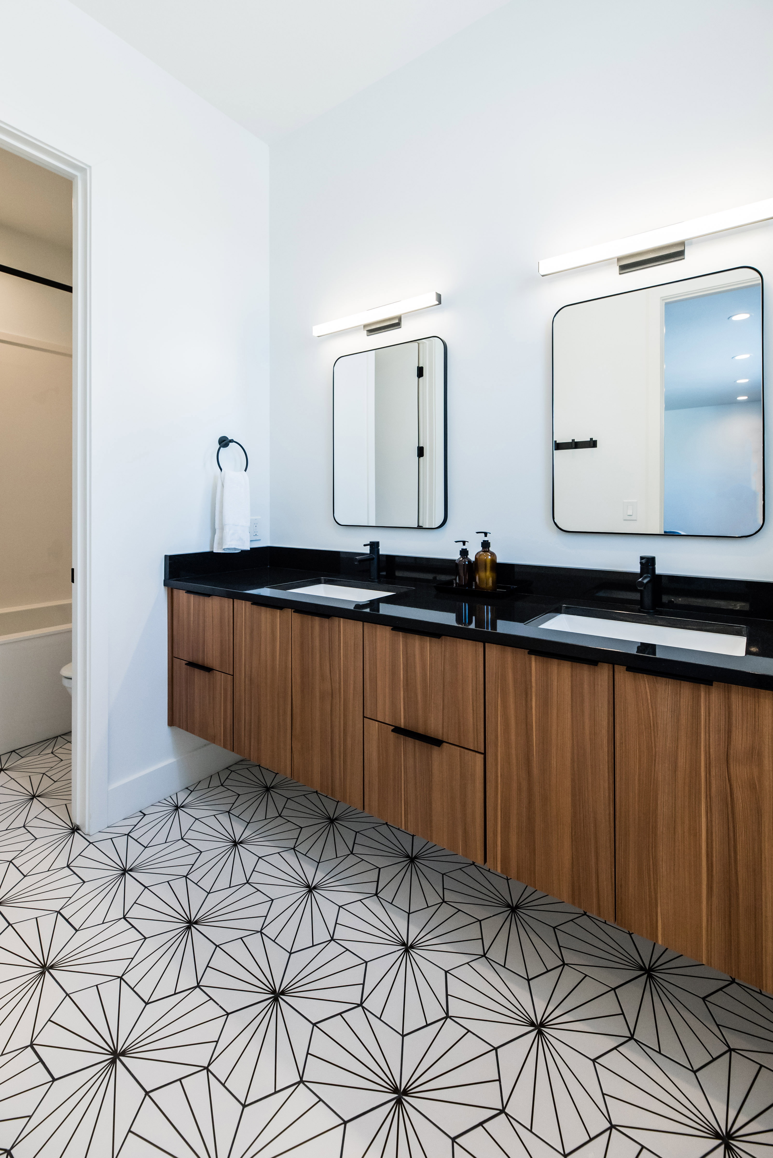 Floating wood-finish vanity with dual integrated sinks and black countertops