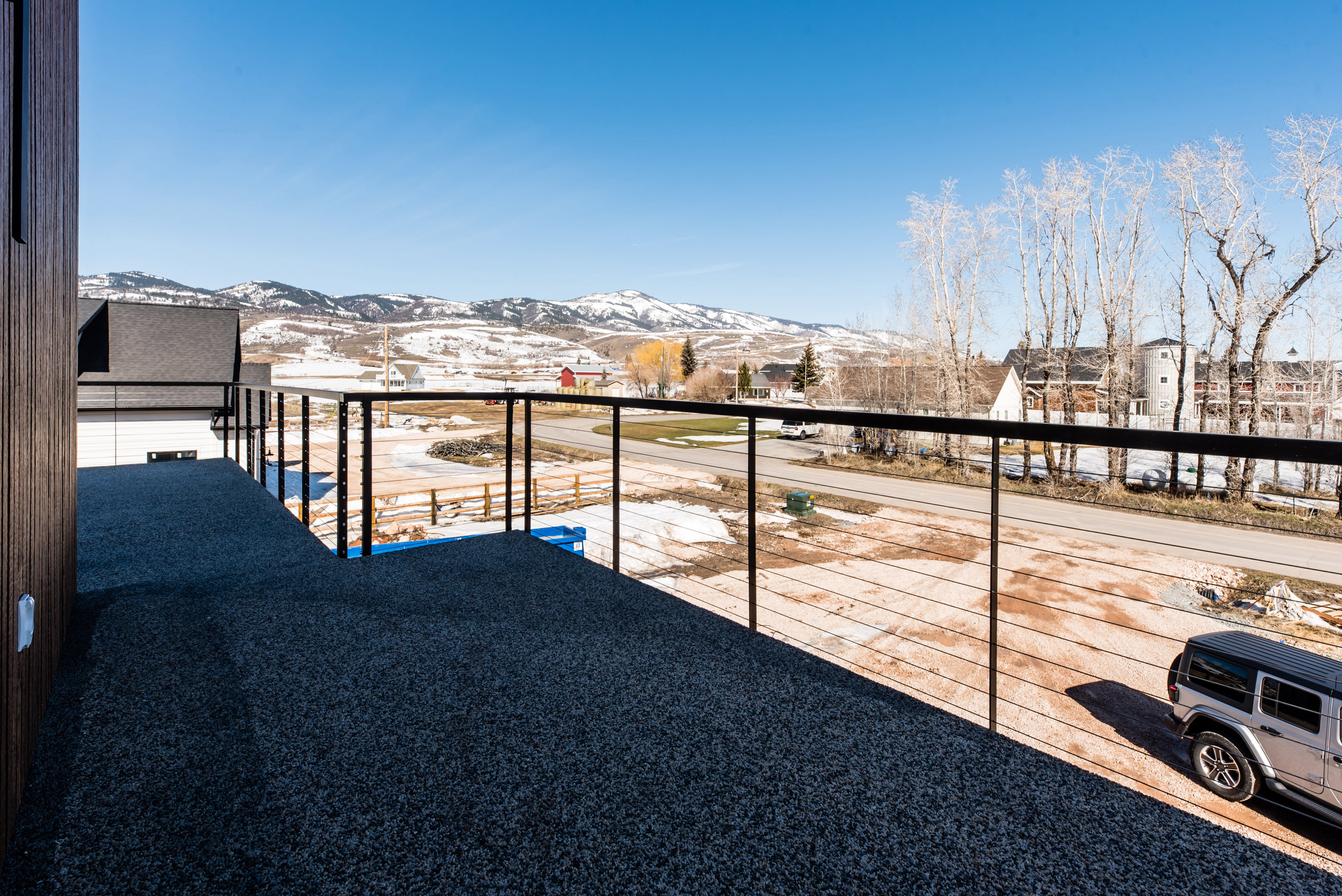 Upper-level deck featuring a dark aggregate surface and modern cable railings