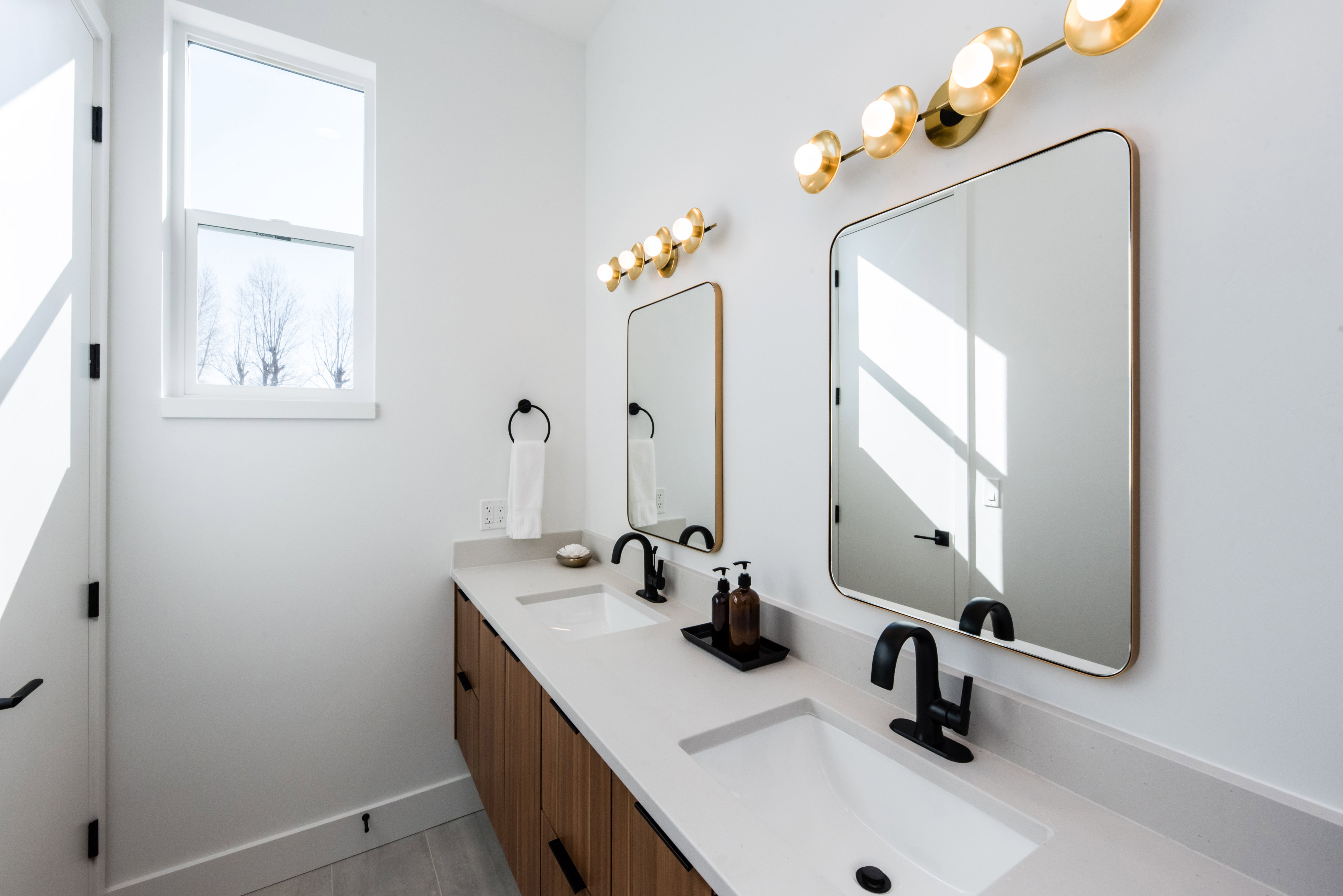 Dual vanity with wood-finish cabinetry, light-toned countertops, and integrated rectangular sinks