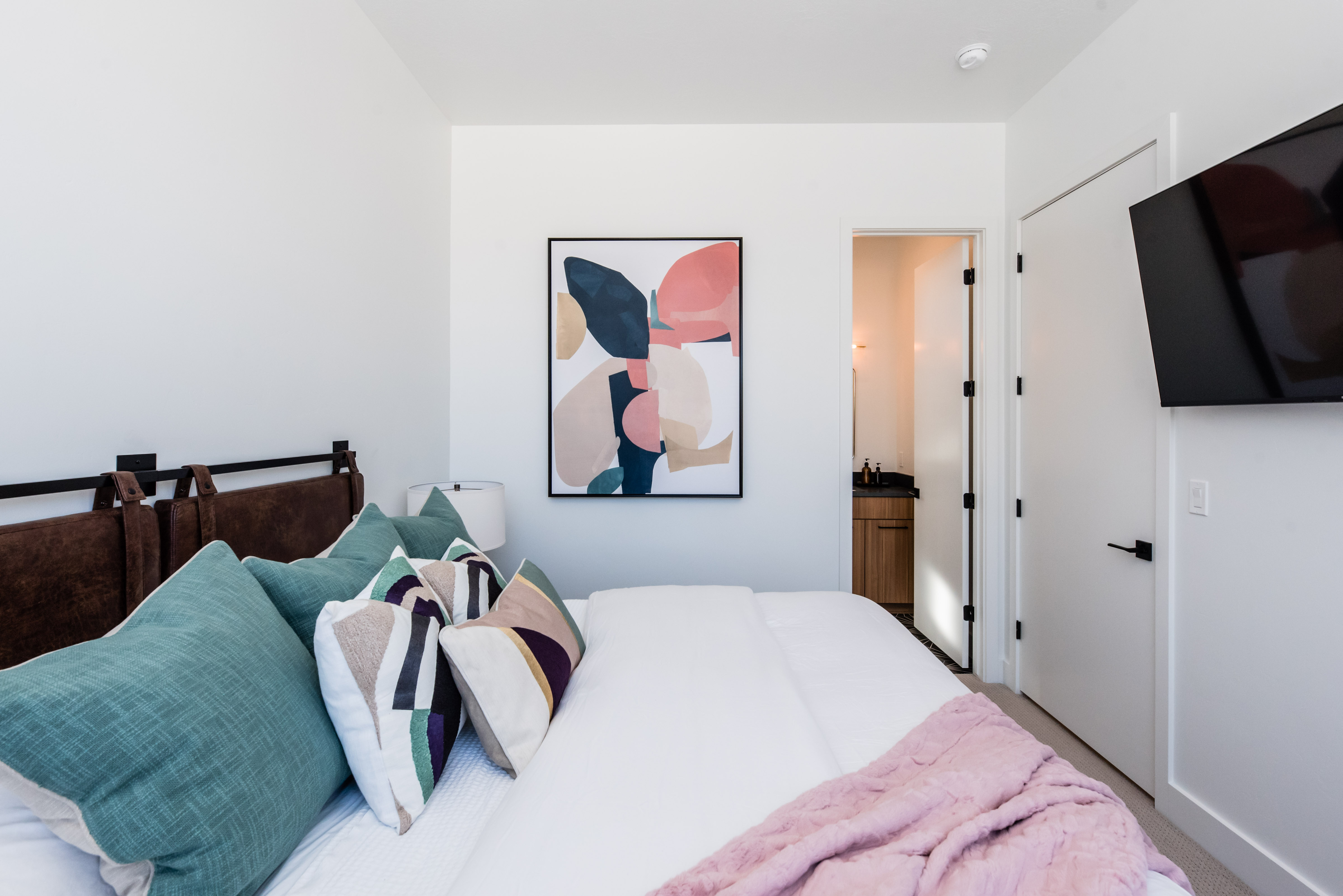 White walls with a contrasting brown headboard and a built-in wall-mounted television