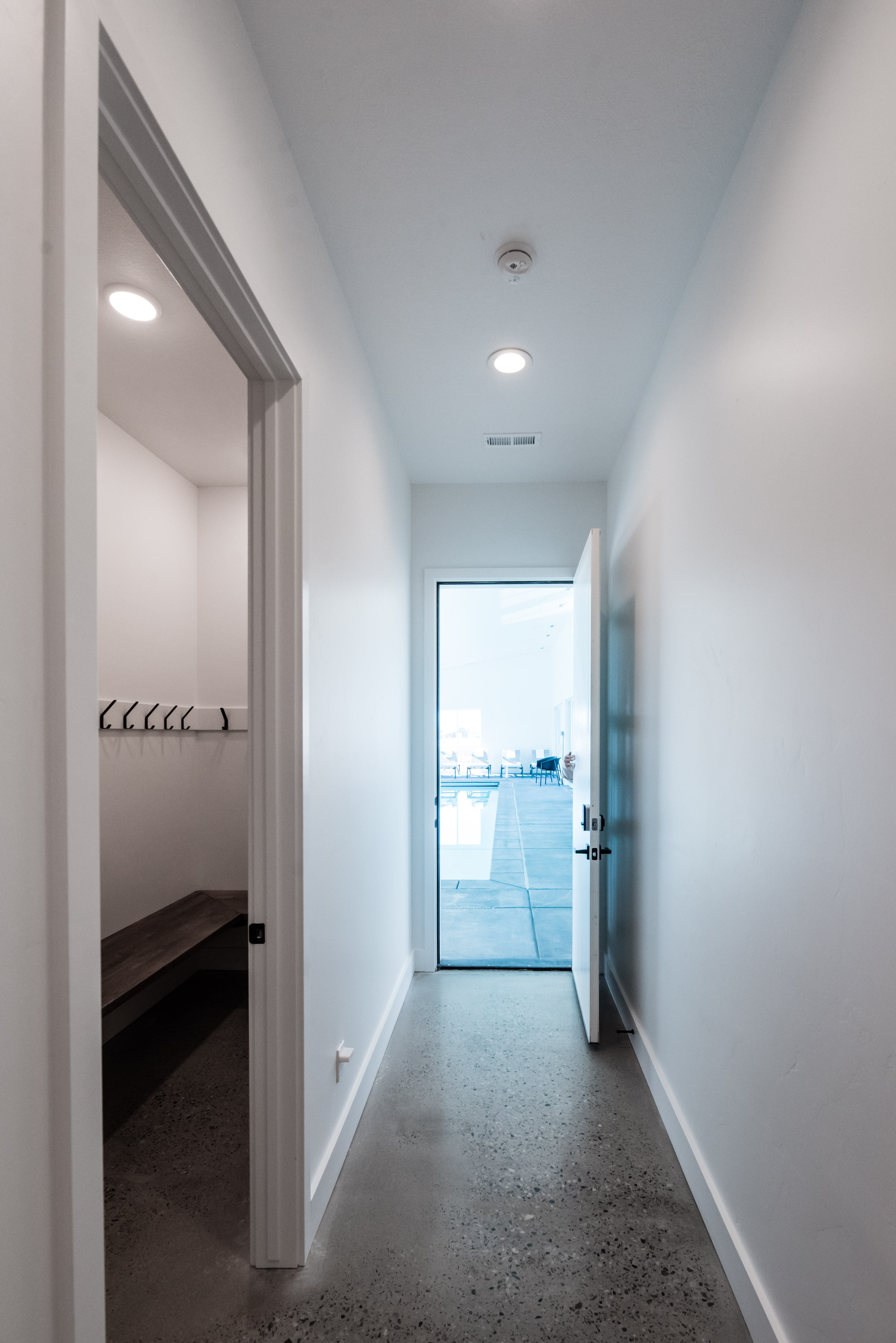 Hallway featuring polished concrete flooring, recessed ceiling lighting, and a white interior door opening to an outdoor area with a pool