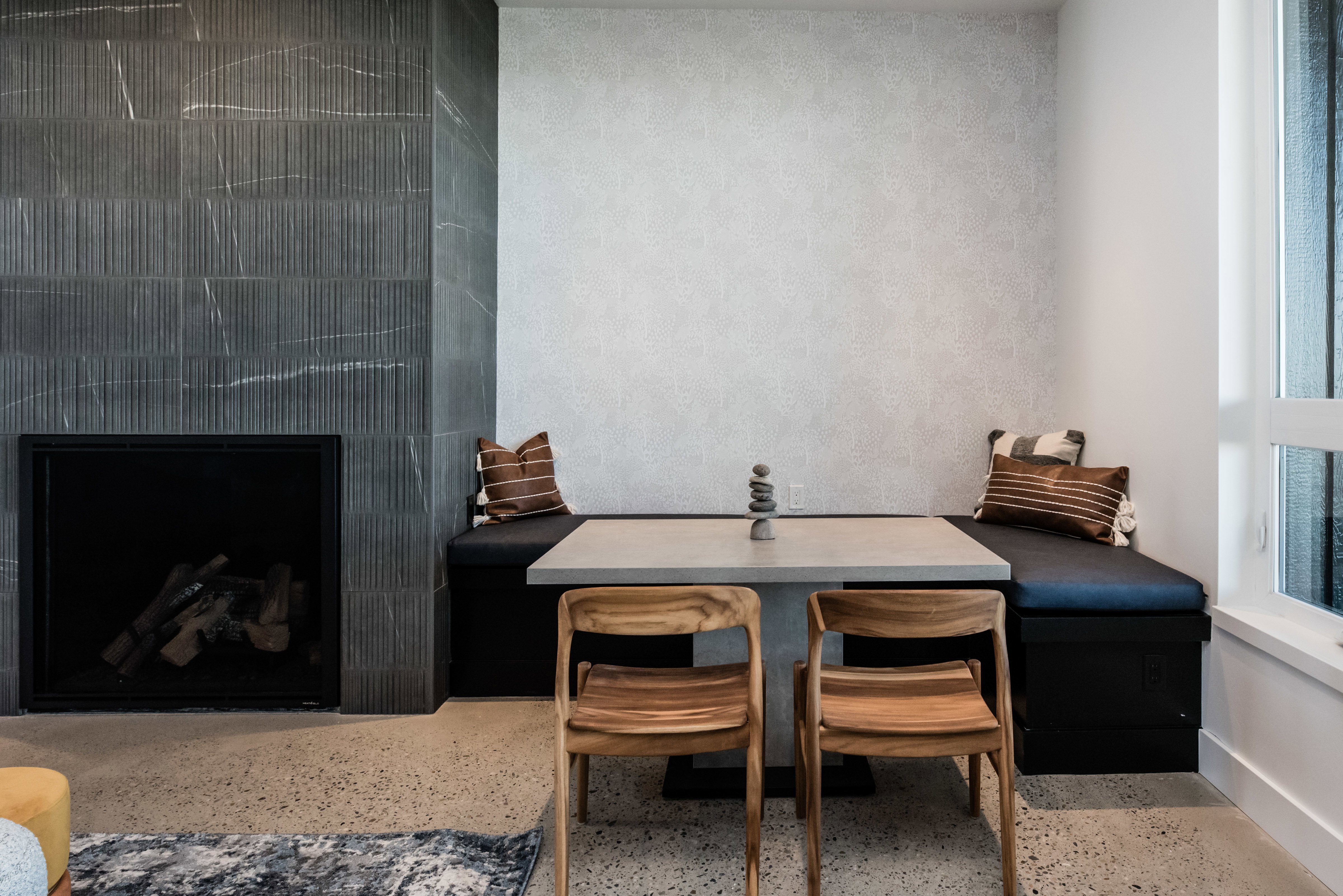 Integrated seating nook with built-in storage, a concrete-finish table, and two wood chairs