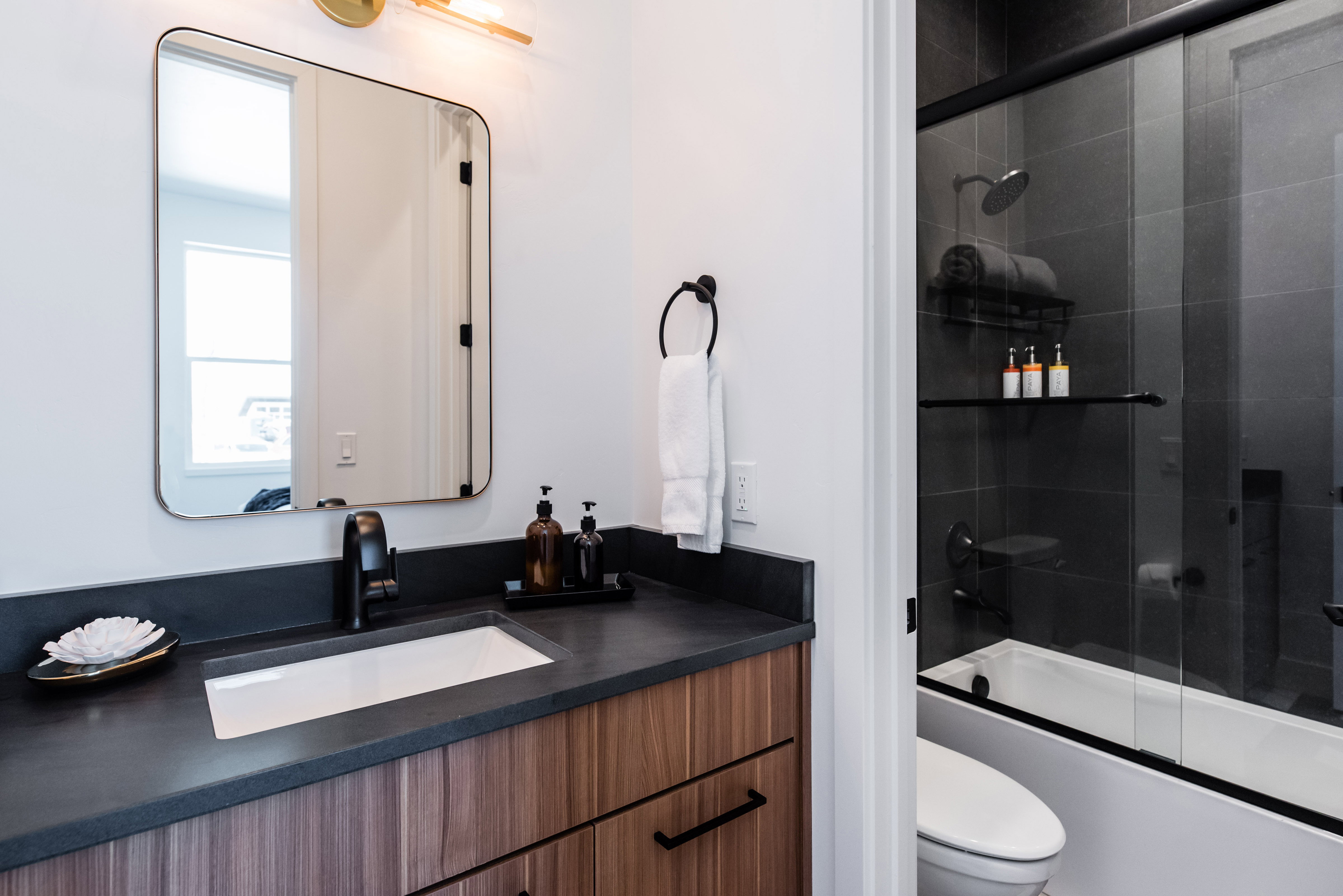 Modern bathroom featuring a wood-finish vanity with a rectangular undermount sink, dark countertop, and matte black faucet