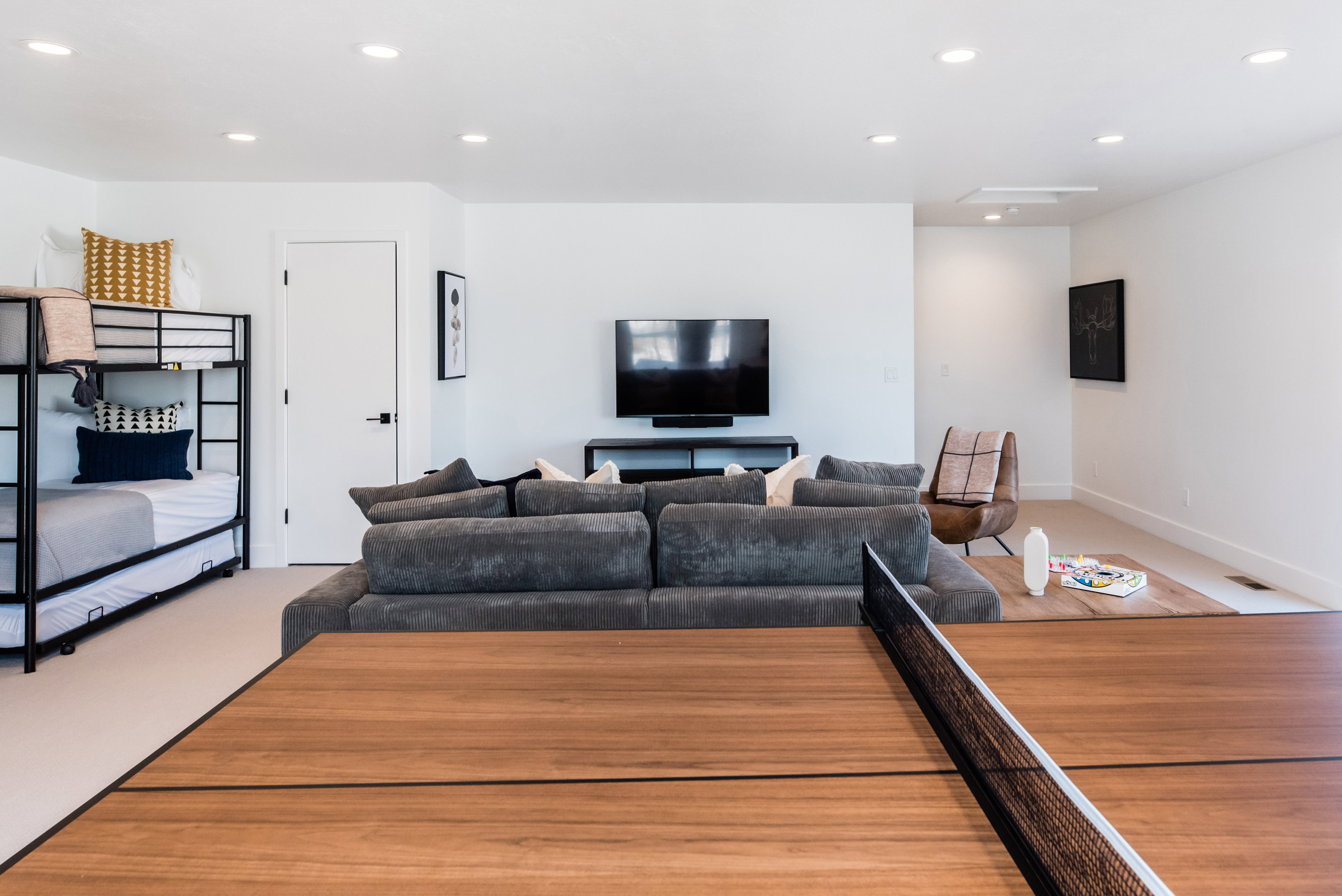 Spacious recreation area featuring a built-in television console, recessed lighting, wood-finish flooring, and light neutral wall colors