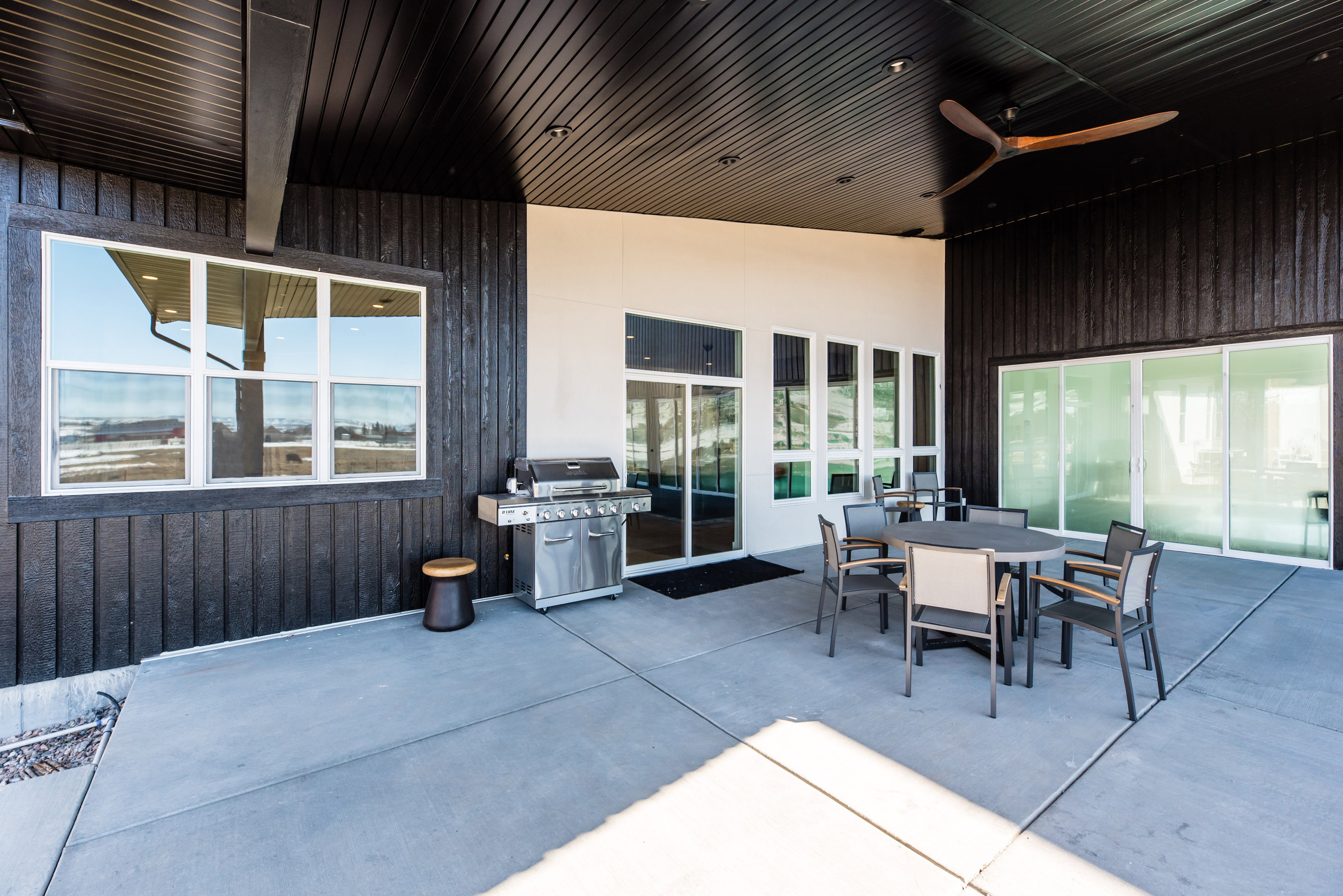 Spacious covered patio featuring concrete flooring, a dark plank ceiling, and recessed lighting