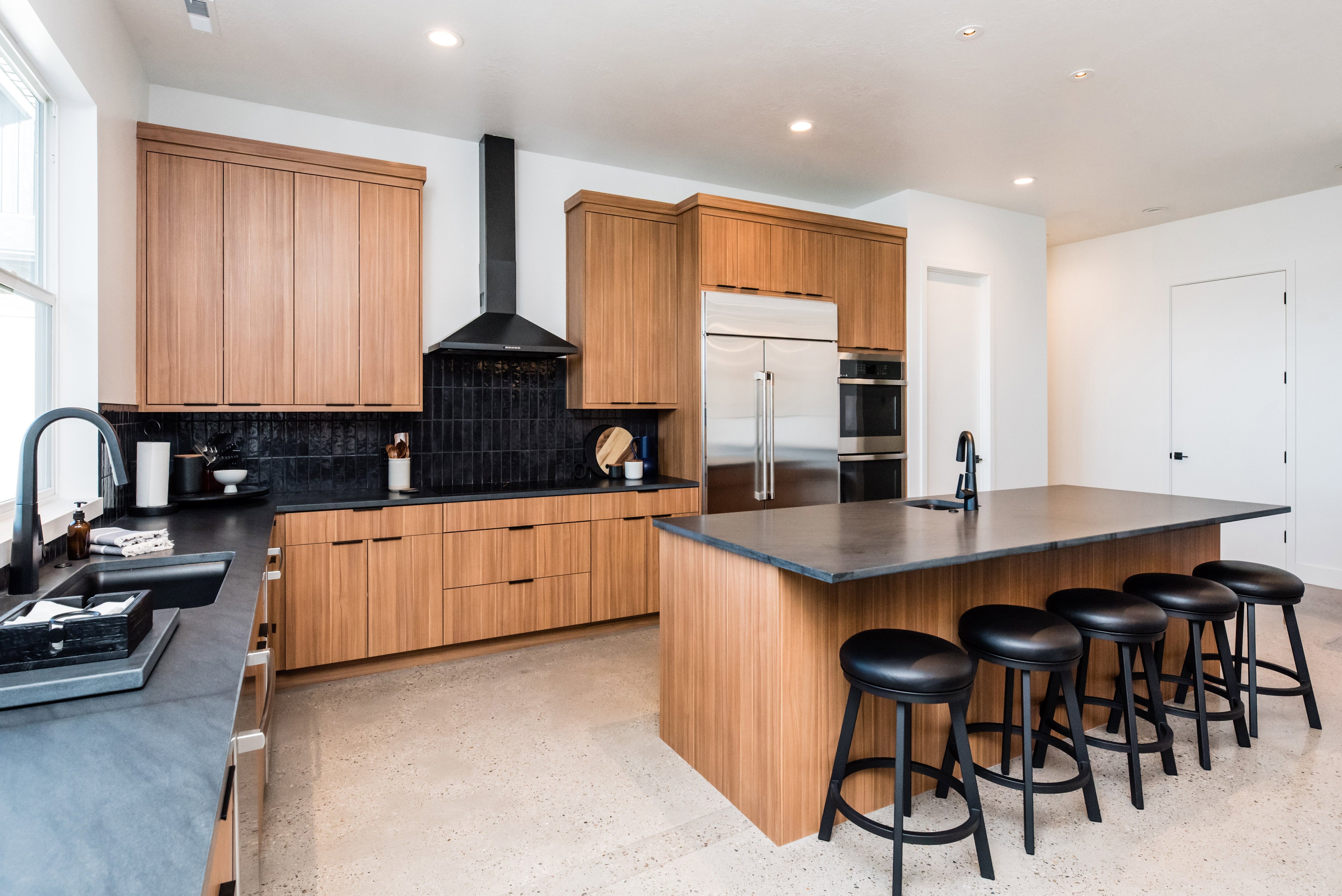Modern kitchen featuring light wood-finish cabinetry, dark countertops, and a full suite of stainless steel appliances