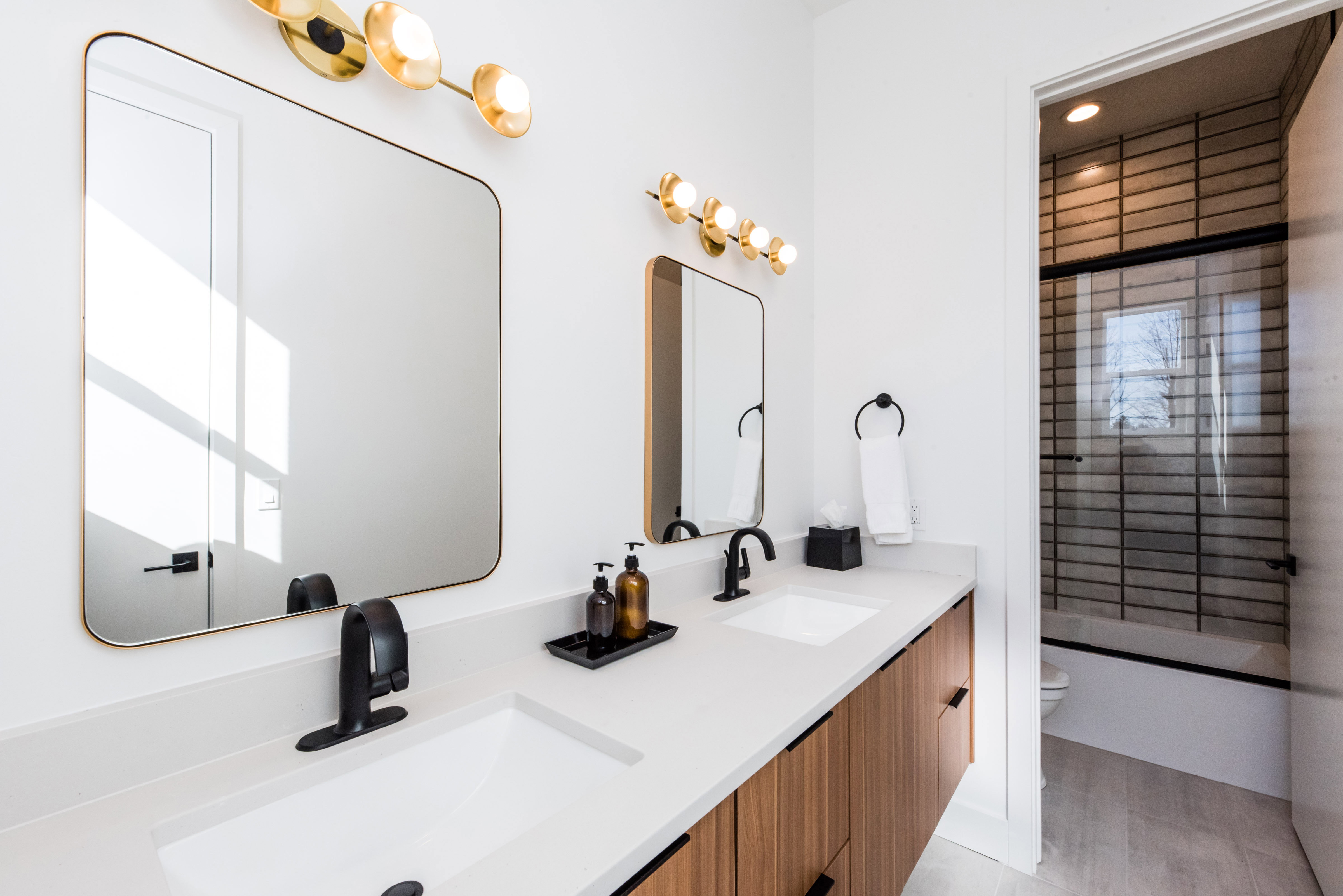 Dual vanity with white undermount sinks, matte black faucets, and light wood-finish cabinetry