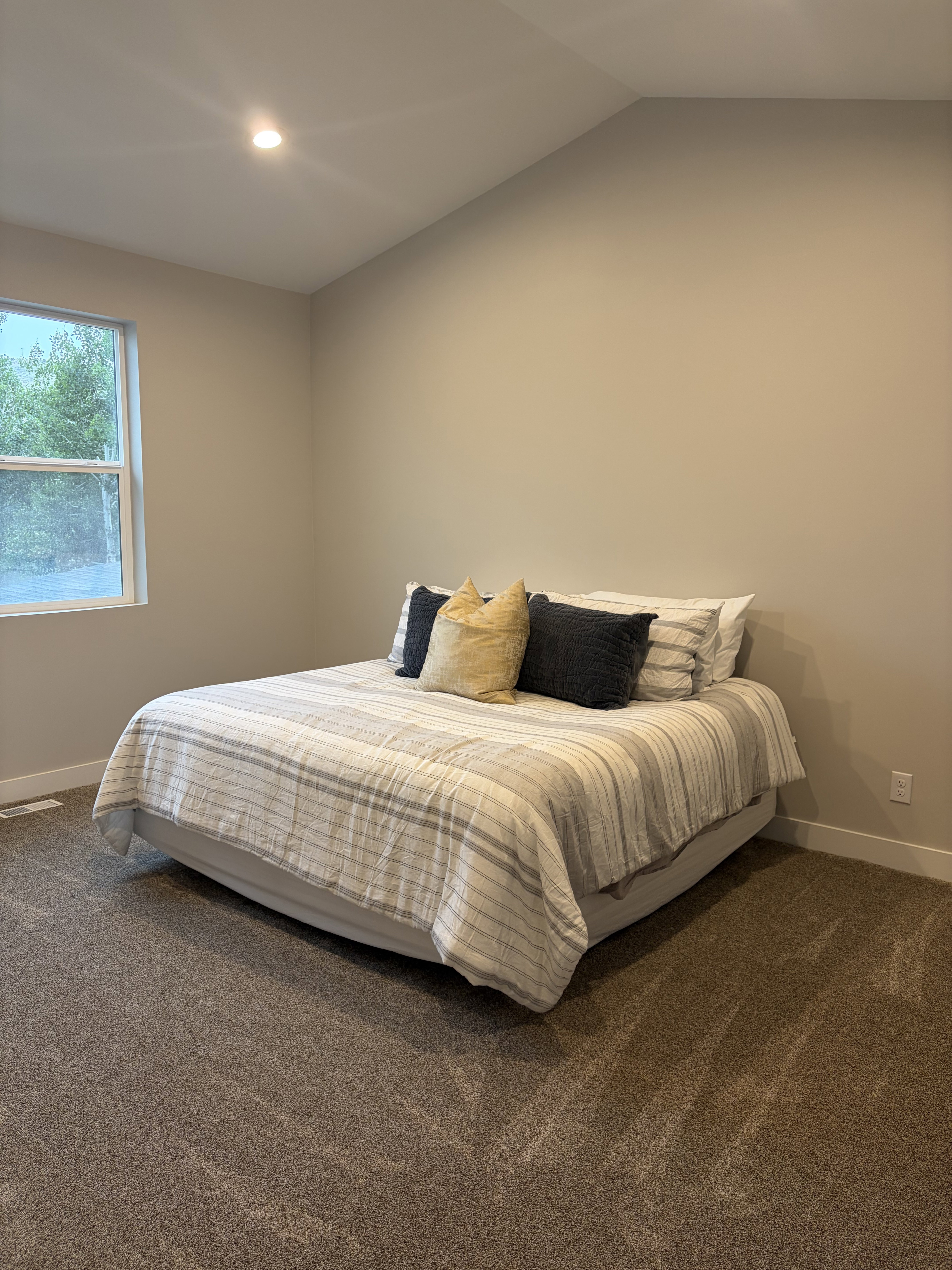 Vaulted ceiling bedroom featuring plush carpeting, a recessed ceiling light, and a white-framed window