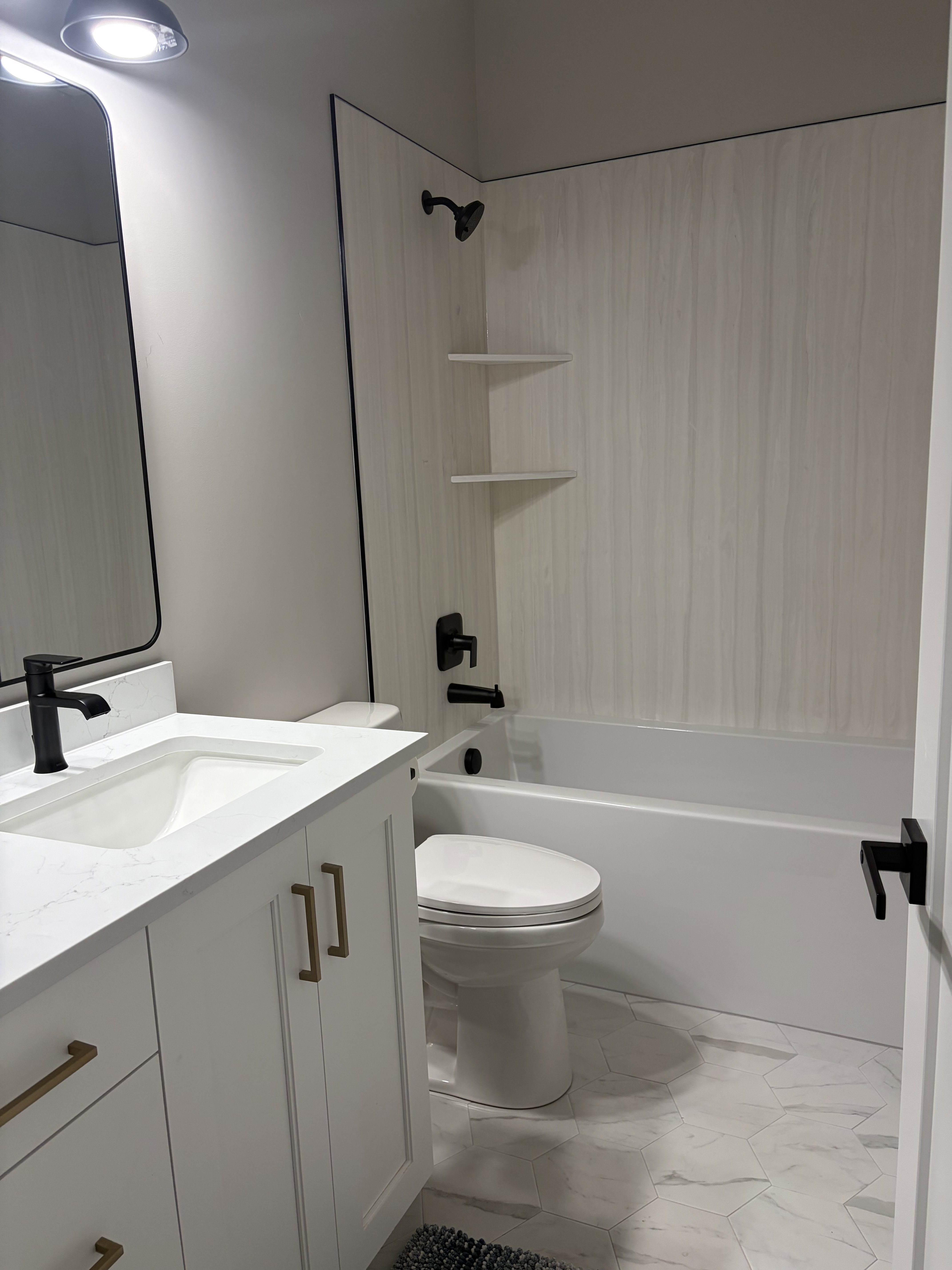 Bathroom featuring a white vanity with gold-tone hardware, a white countertop with an integrated sink, and matte black plumbing fixtures