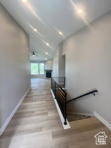 Hallway featuring wood-finish flooring, recessed lighting, and a modern horizontal bar railing