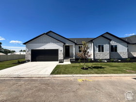 Contemporary exterior featuring a white siding and stone façade, black trim, a dark garage door, and a manicured lawn with a young tree
