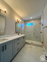 Bathroom featuring a dual vanity with light blue cabinetry, white countertops, and bronze hardware